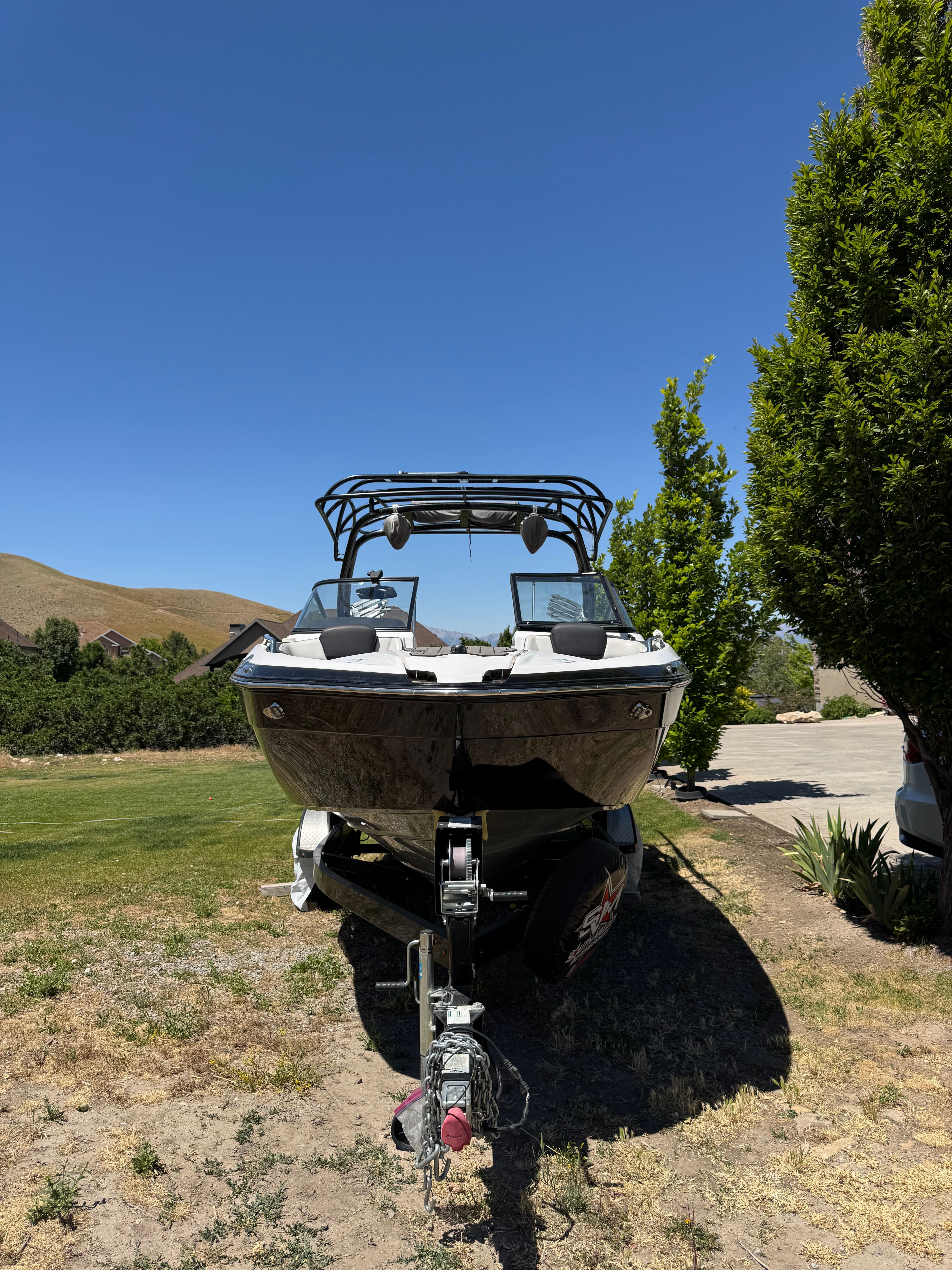 A 2017 Yamaha 242X E-Series boat on a trailer, parked on dry grass.