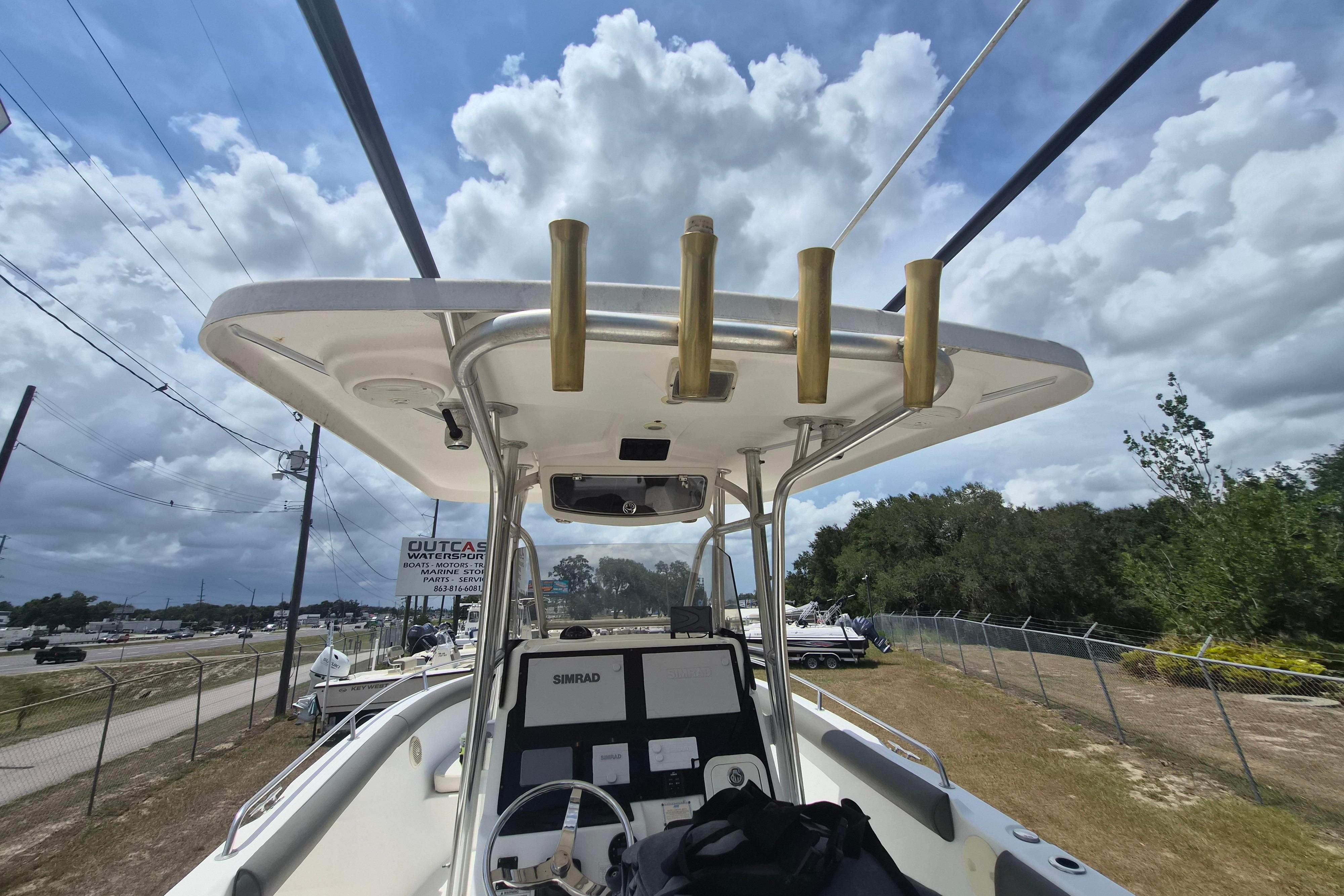 2006 Century 2900 Center Console boat with T-top and electronics, parked outdoors under cloudy sky.