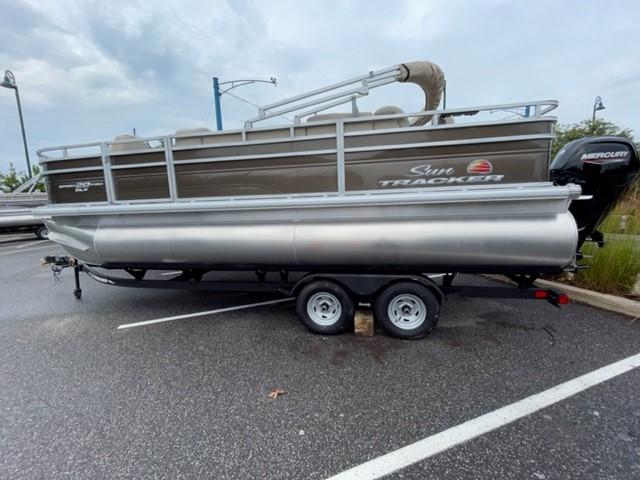 2024 Sun Tracker SportFish 20 DLX pontoon boat on trailer in parking lot.