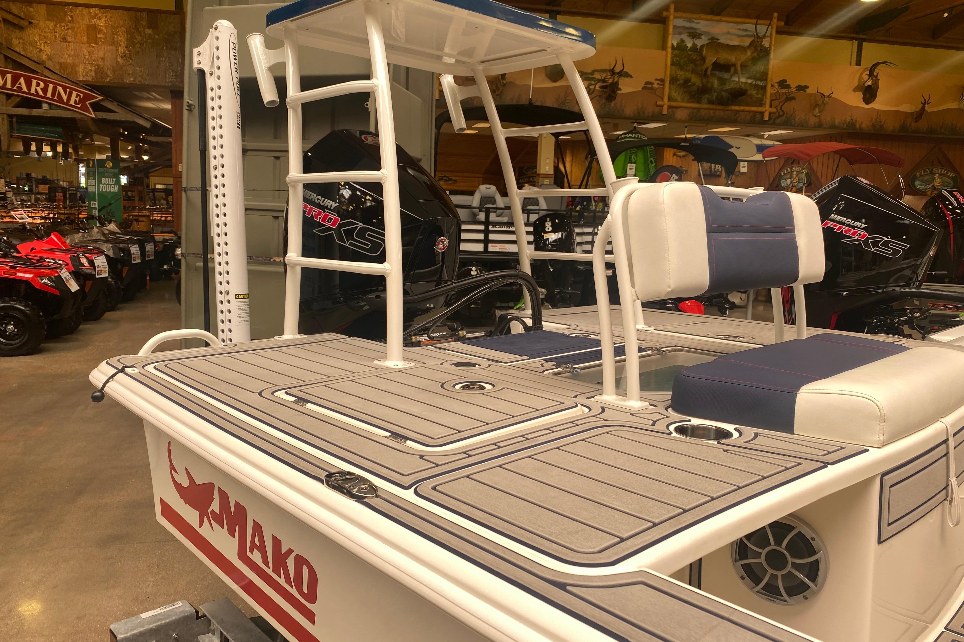 2025 Mako 18 Pro Skiff Patriot Edition boat displayed indoors, featuring seating and storage.
