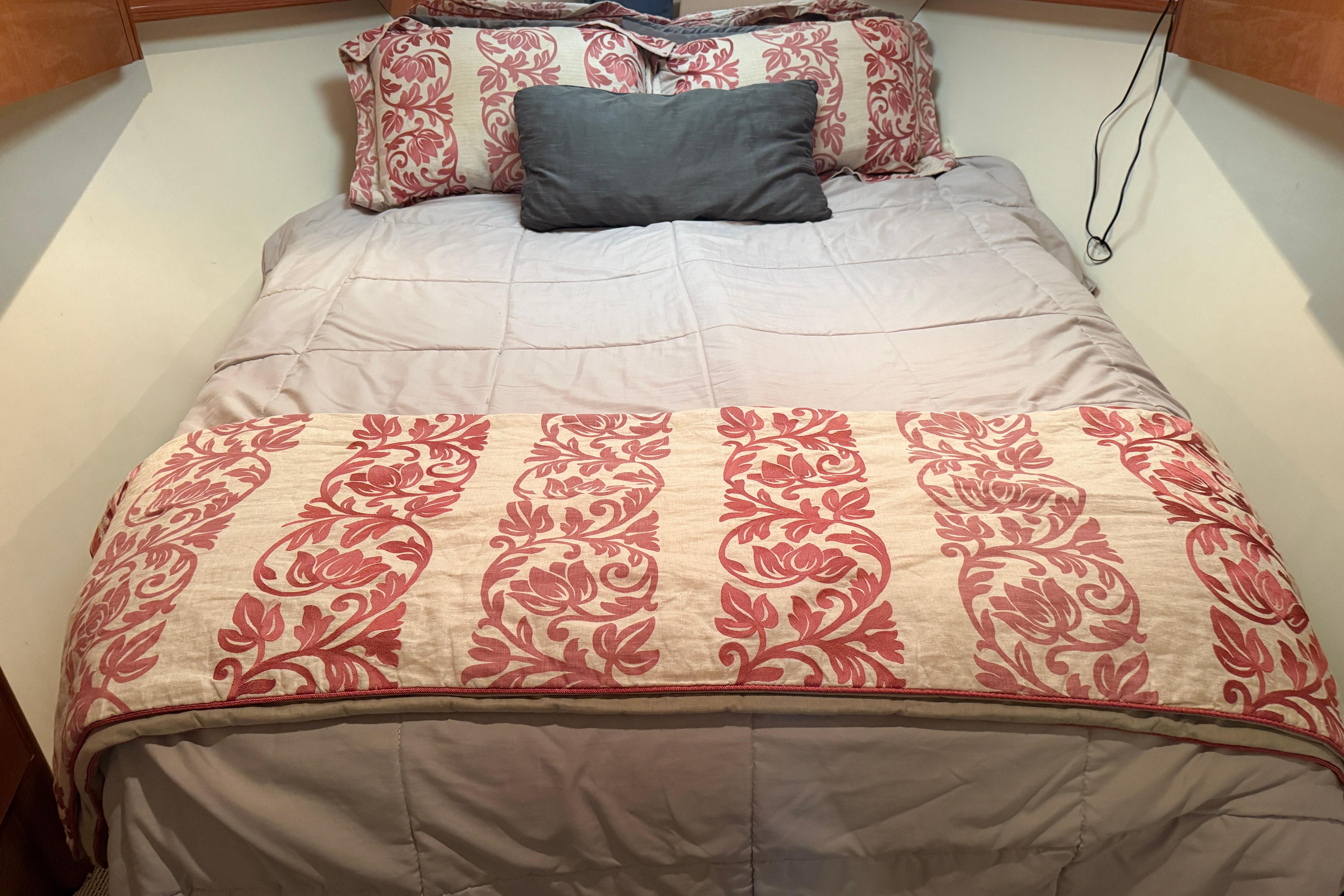Cozy bed with floral bedding in a 2000 Viking 55 Convertible yacht cabin.