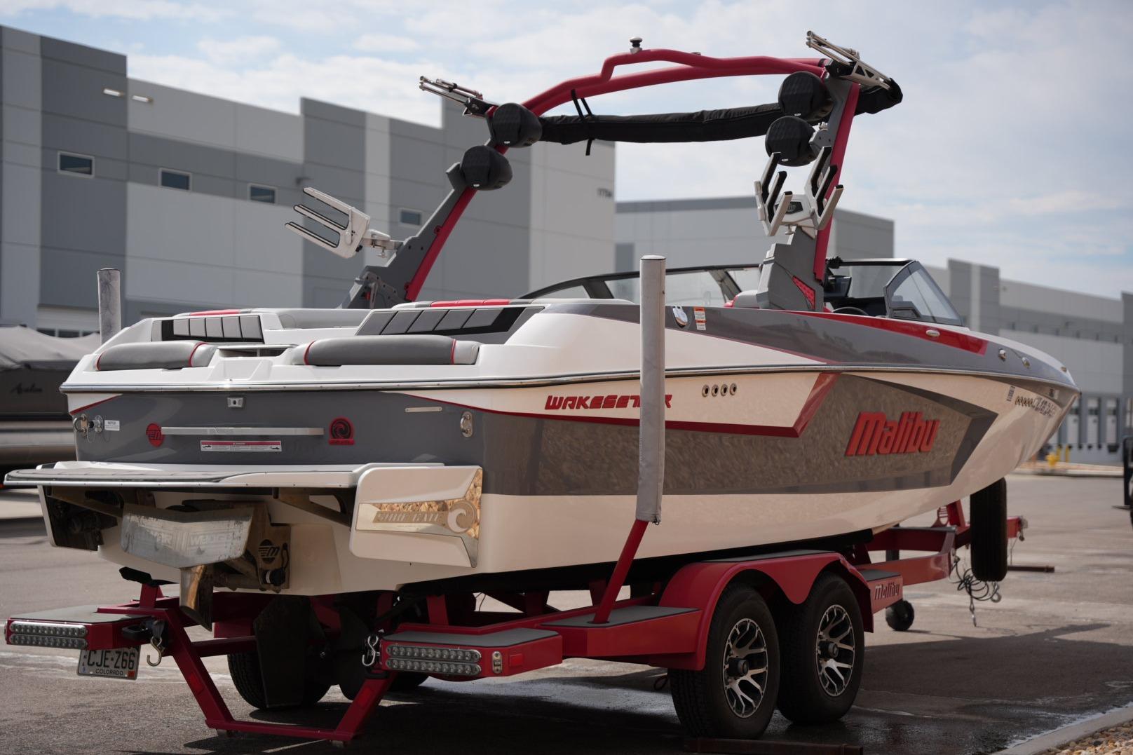 2022 Malibu Wakesetter 23 MXZ boat on trailer, parked outdoors near industrial buildings.
