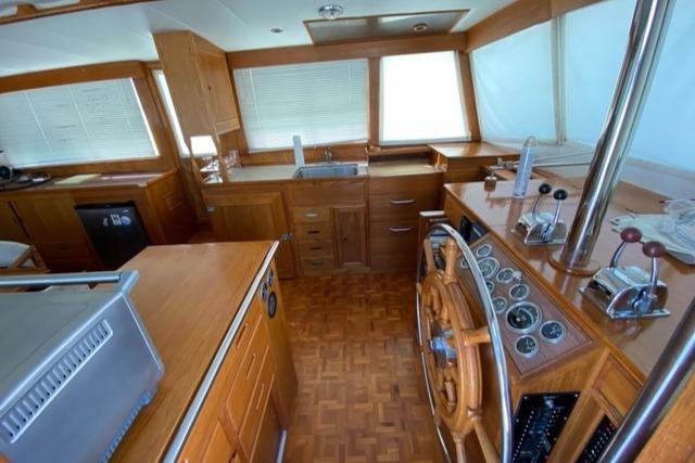 1977 Grand Banks 42 interior with wooden helm, kitchen, and navigation controls.