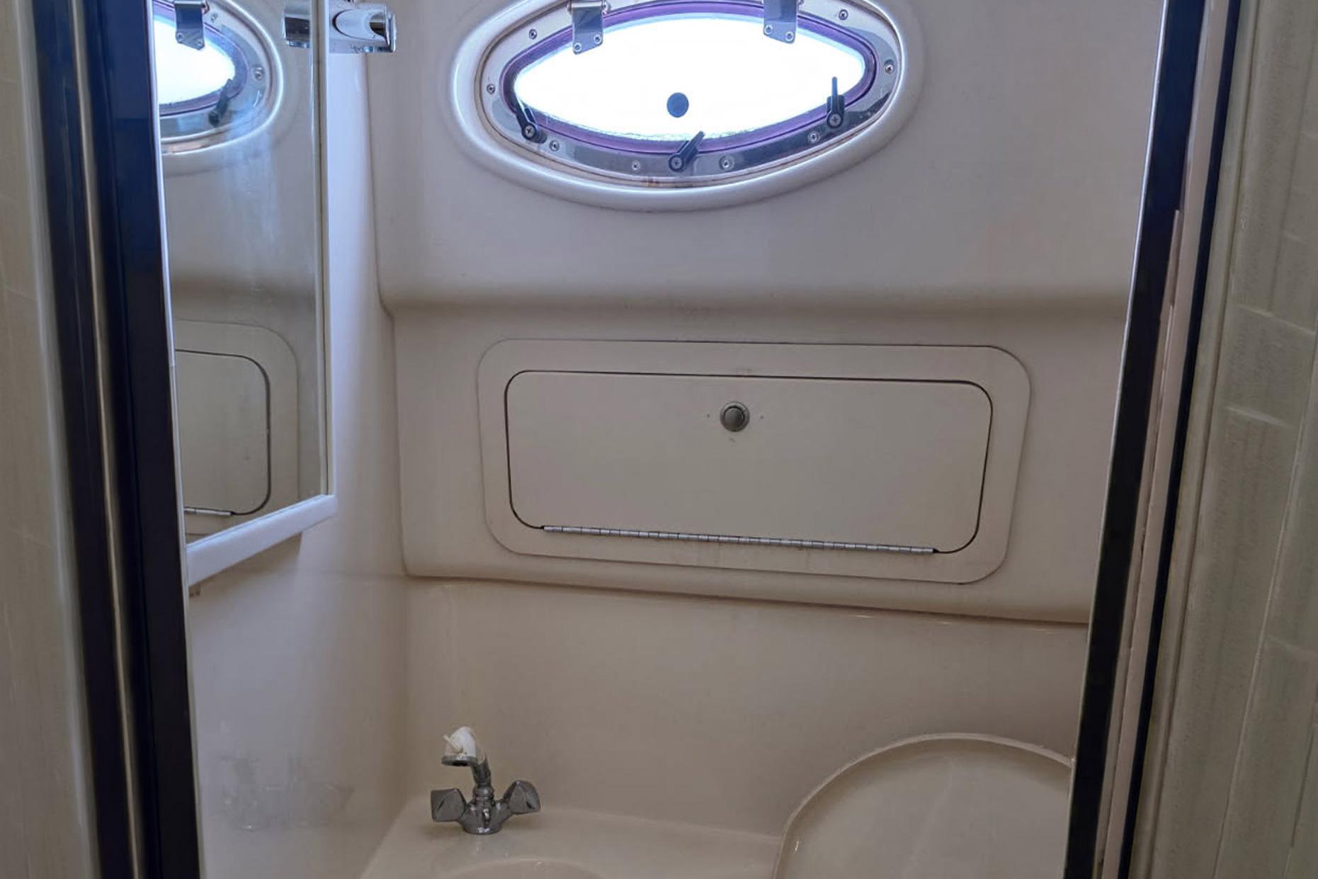 Bathroom interior of 1998 Sea Ray Sundancer 400 yacht with oval window and sink.