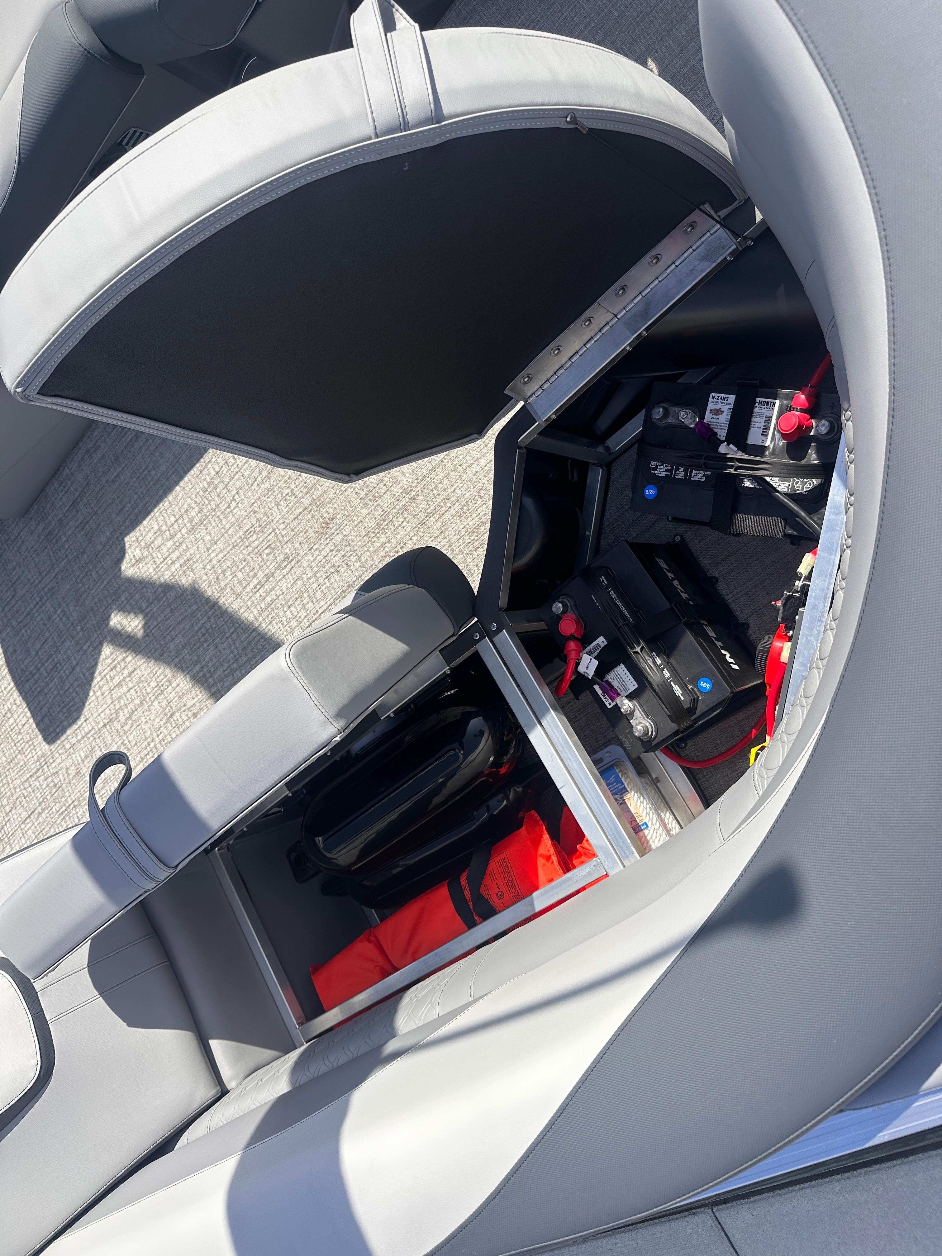 Open storage compartment in 2025 Avalon LSZ Quad Lounger, showing battery and safety equipment.
