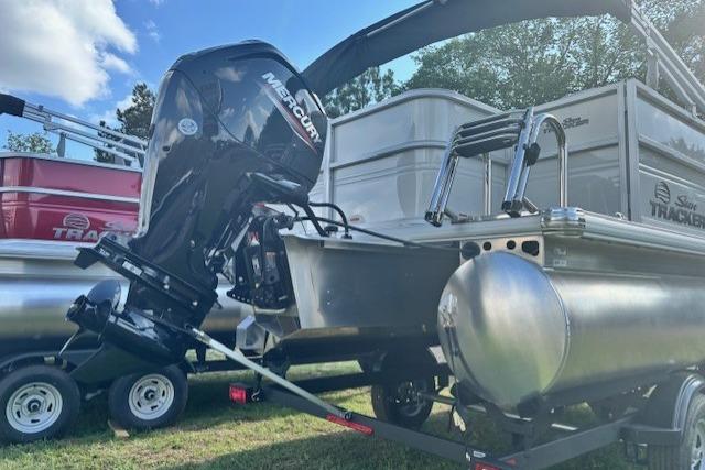 2026 Sun Tracker Party Barge 18 DLX pontoon boat with Mercury outboard motor, parked on trailer.