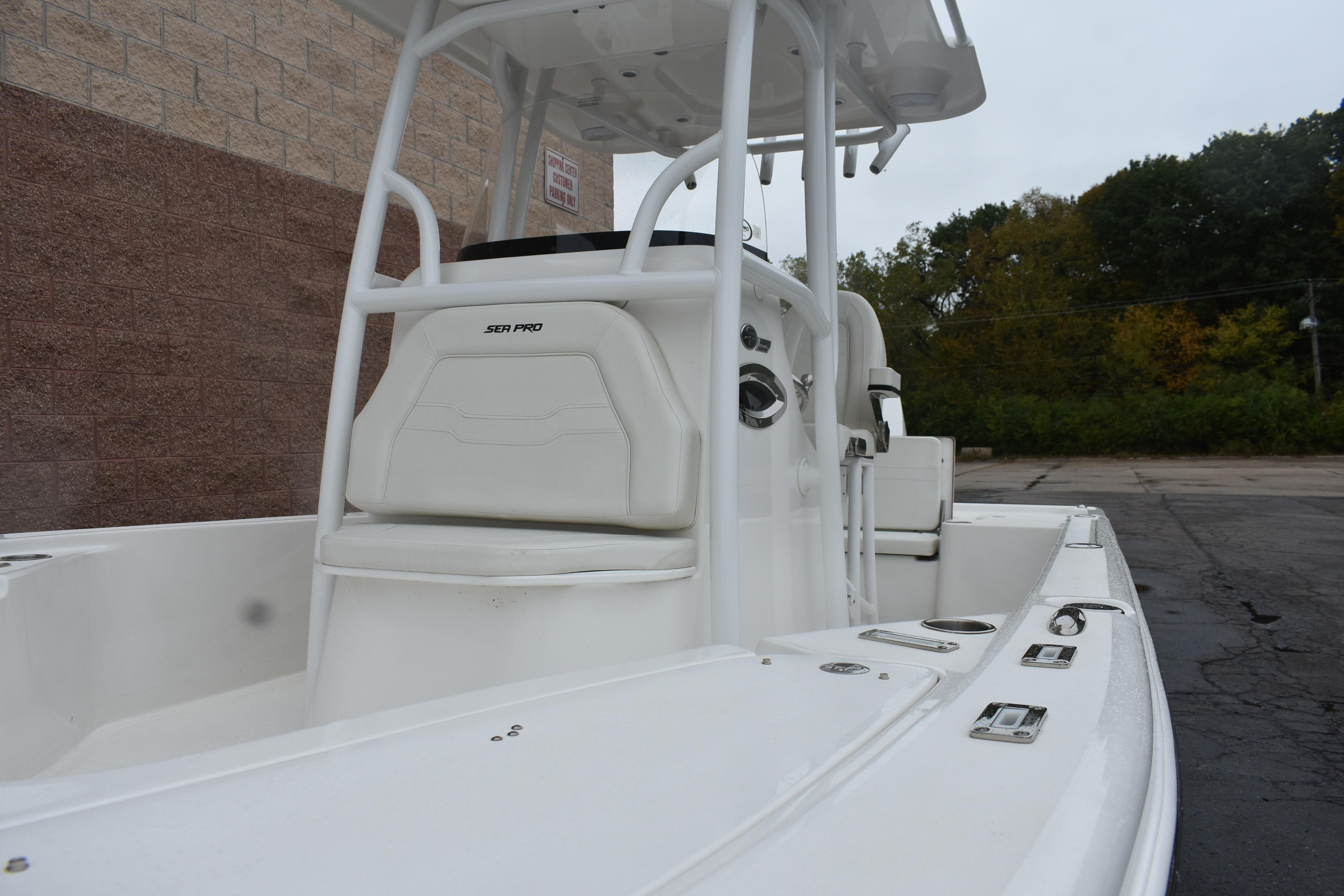 2025 Sea Pro 250 Bay boat, white interior, parked outdoors near brick wall.