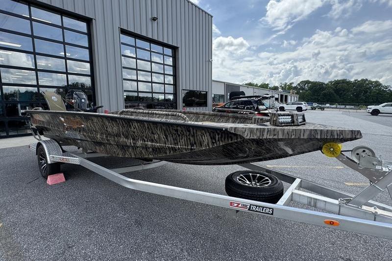 2026 Excel 183 Tomahawk boat on trailer outside industrial building under cloudy sky.