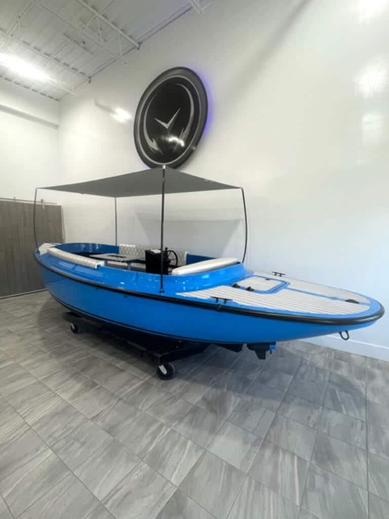 2024 Vision Marine Technologies Fantail 217 electric boat in showroom, blue with canopy.