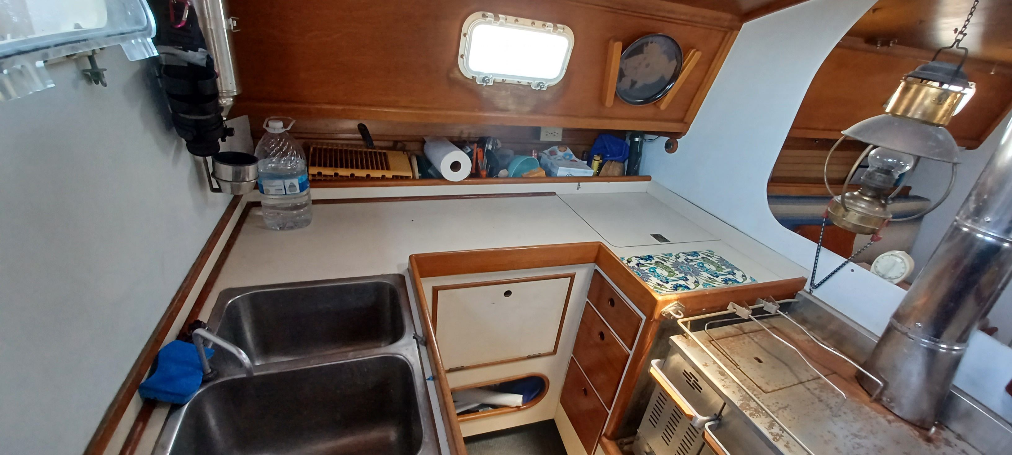 Interior of a sailboat with sink, stove, and wooden paneling.