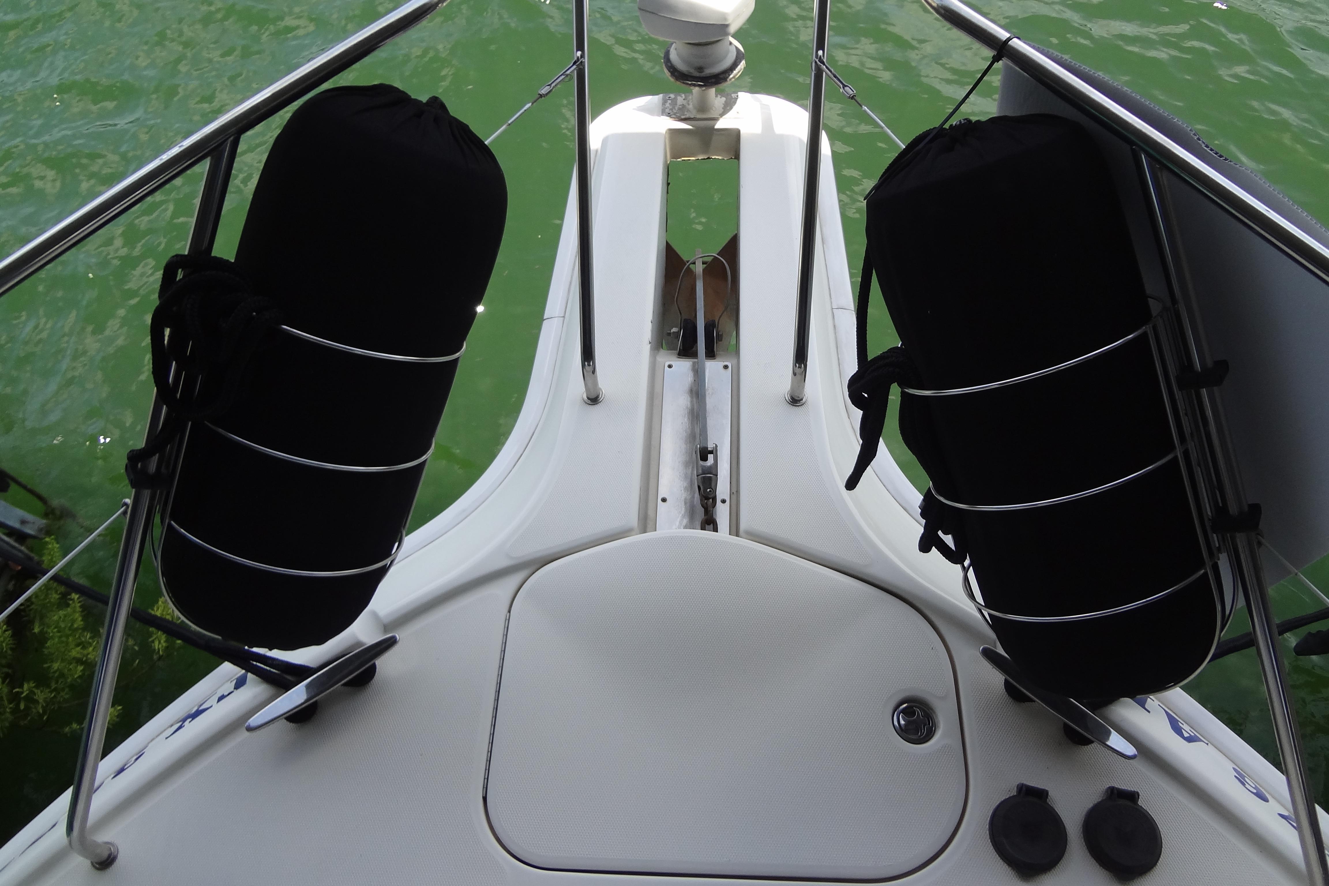 Bow view of 2005 Silverton 34 Convertible yacht with black fenders on green water.