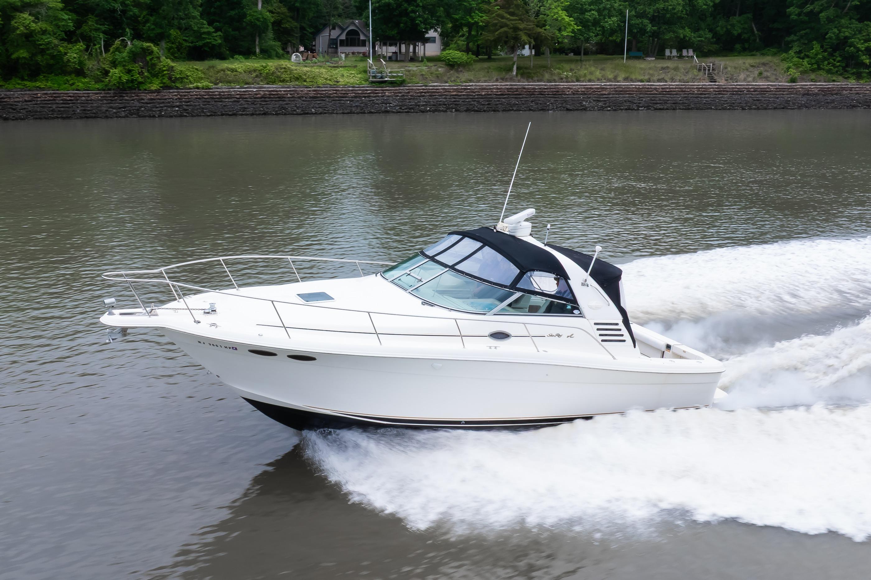1998 Sea Ray 330 Express cruising on a river with lush green shoreline.