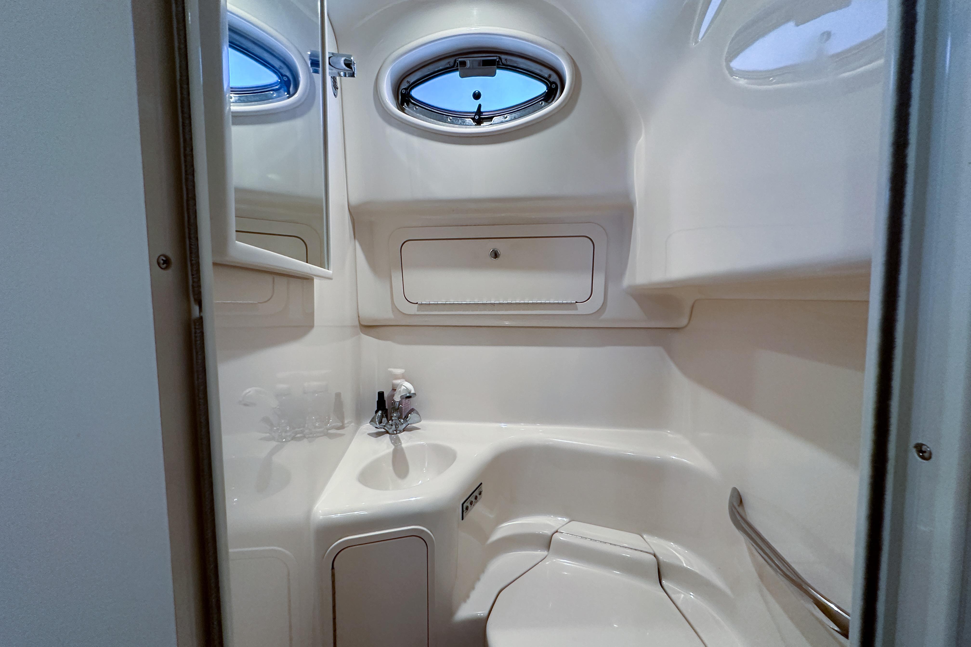 Compact bathroom in a 2001 Sea Ray 410 Sundancer yacht, featuring a sink and porthole window.