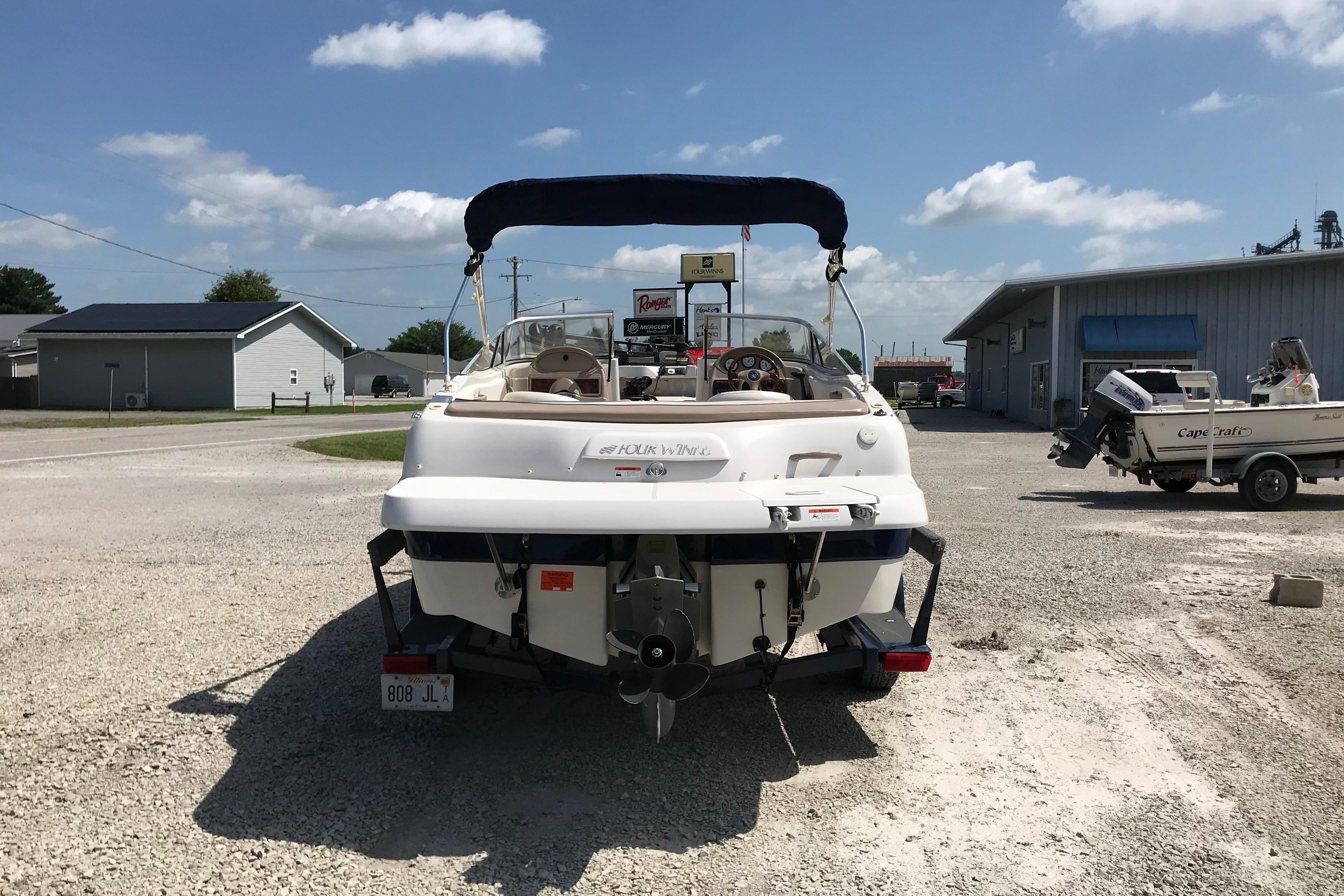 2005 Four Winns 180 Horizon FS boat parked on gravel lot under blue sky.