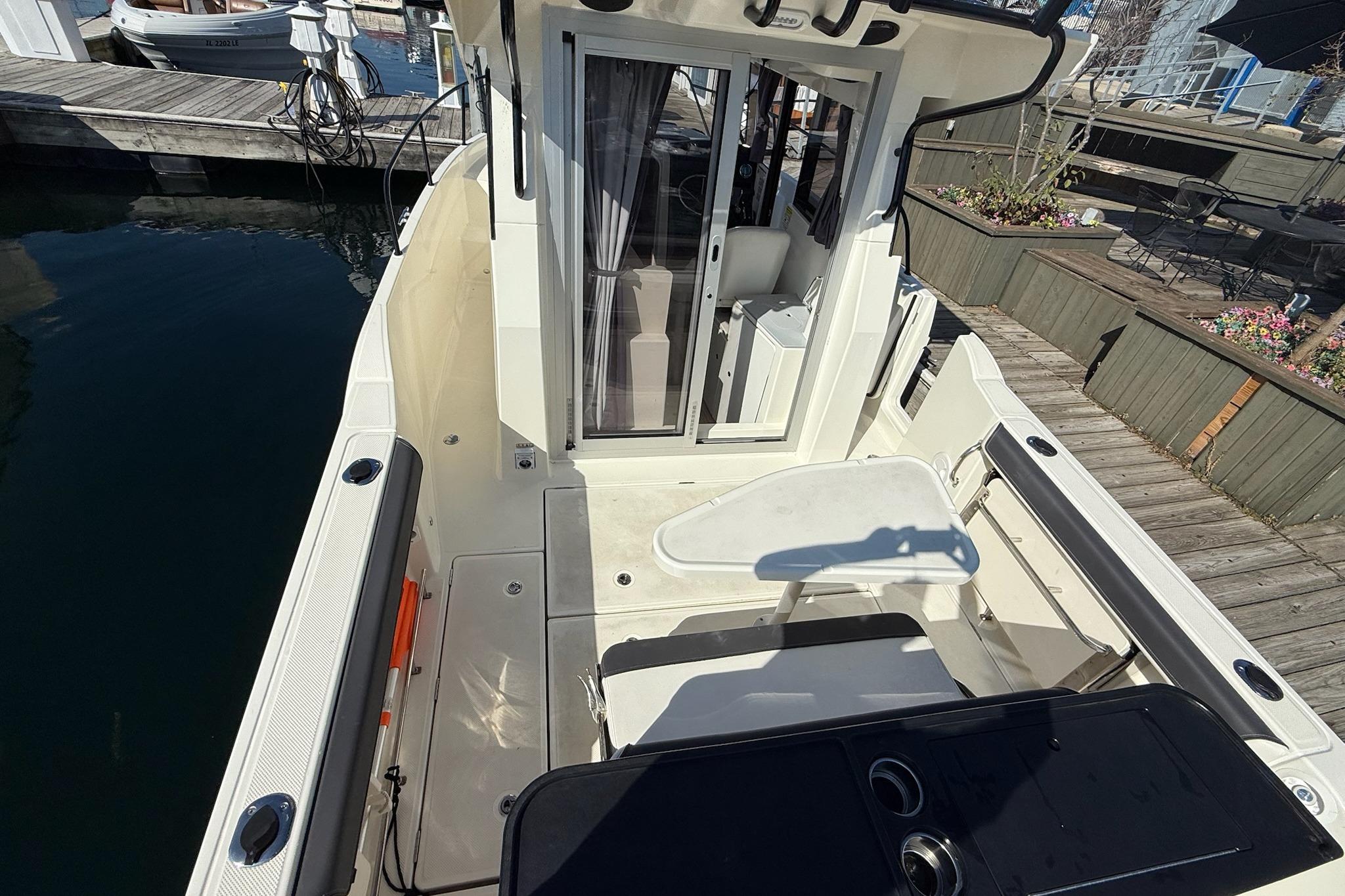 2024 Bayliner Trophy T25 Pilothouse boat docked, showcasing spacious deck and pilothouse entrance.