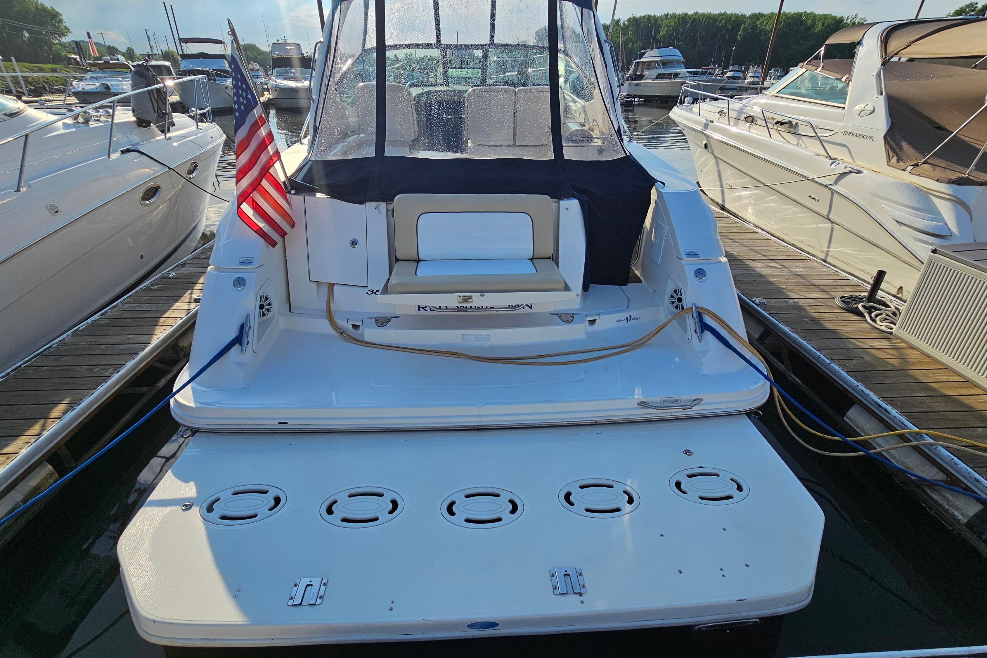 2008 Sea Ray Sundancer 350 docked, rear view with American flag, sunny marina setting.