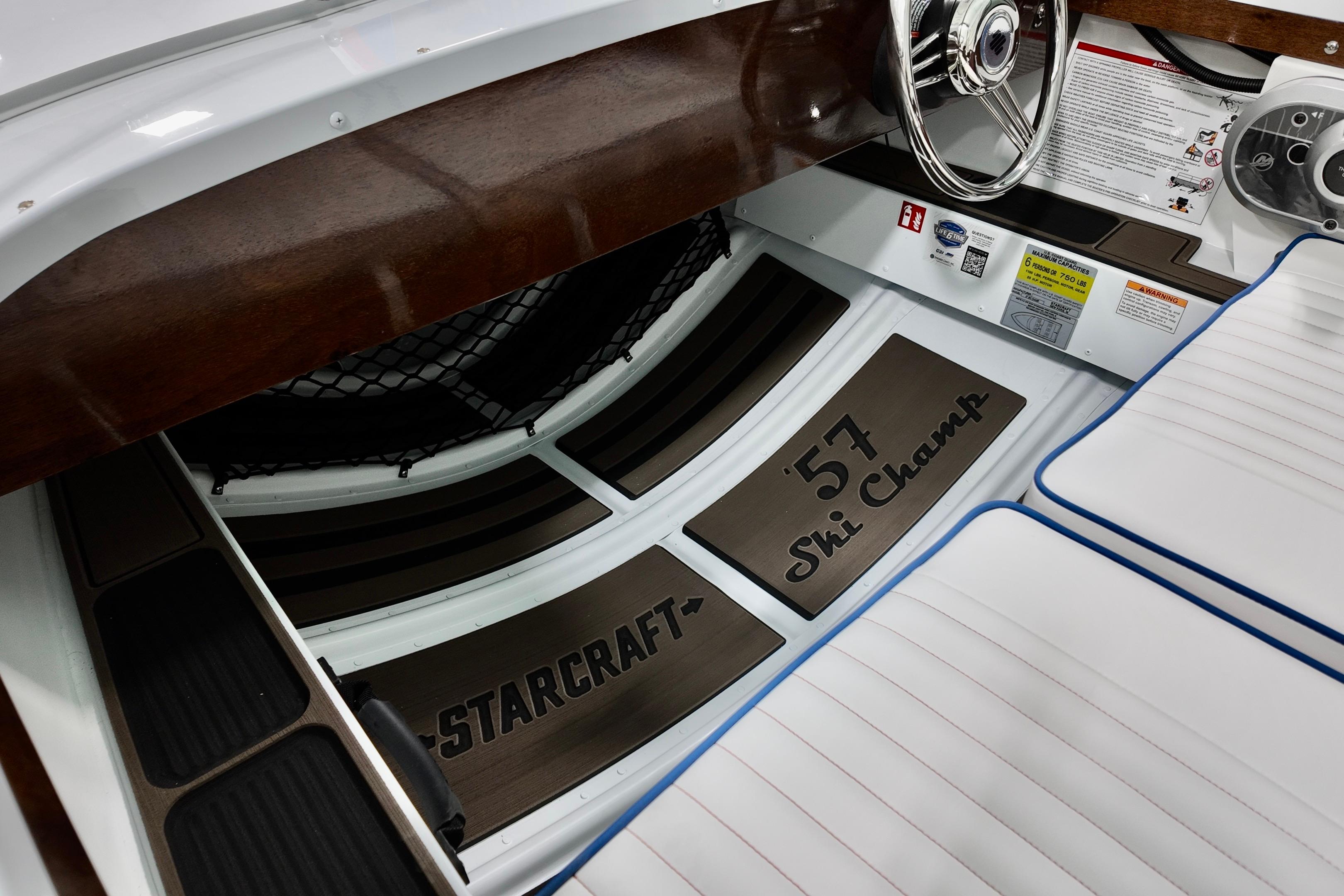 Interior of 2026 Starcraft 57 Ski Champ boat with steering wheel and branded flooring.