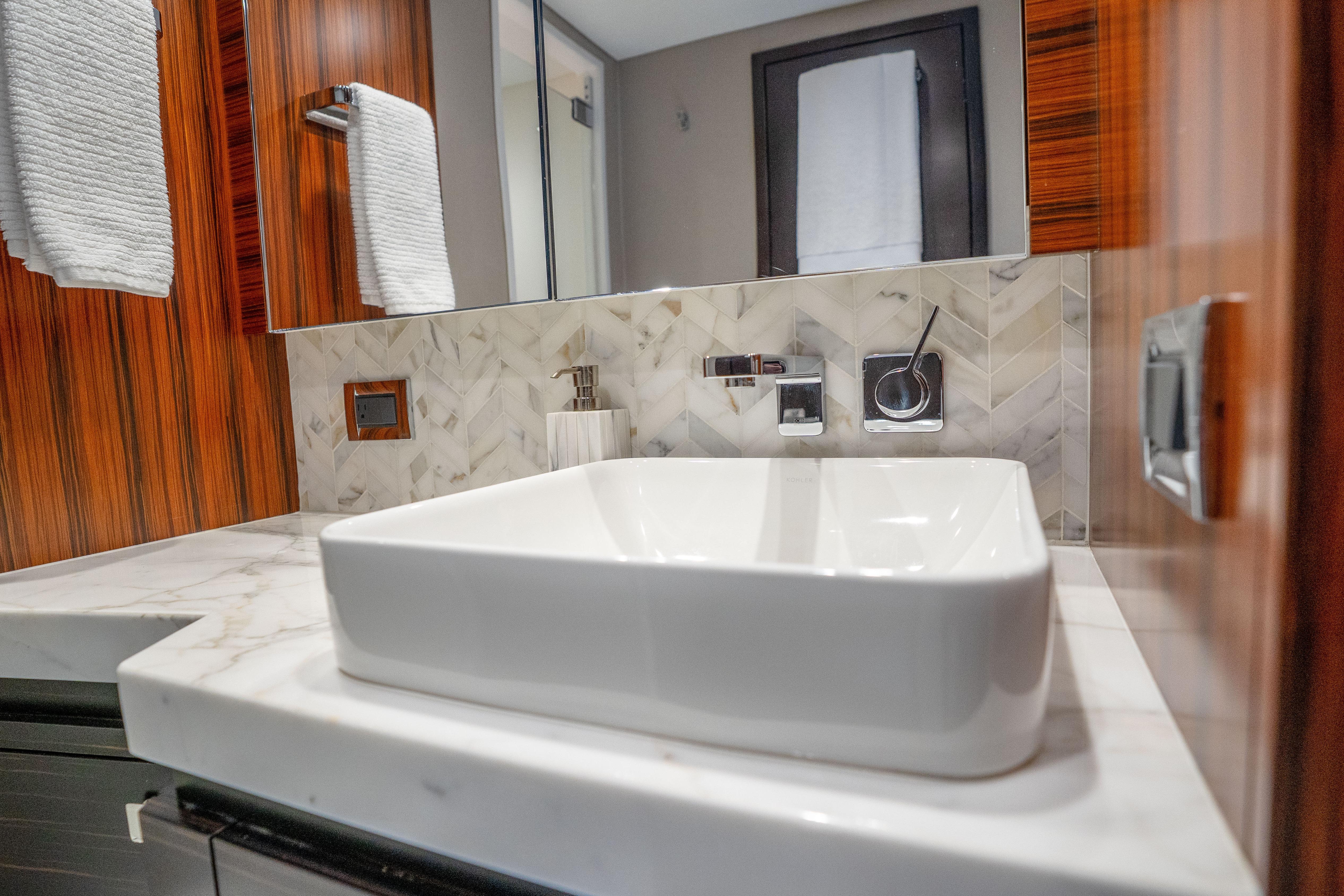 Luxurious bathroom sink in 2021 Hatteras M75 Panacera yacht with elegant wood accents.