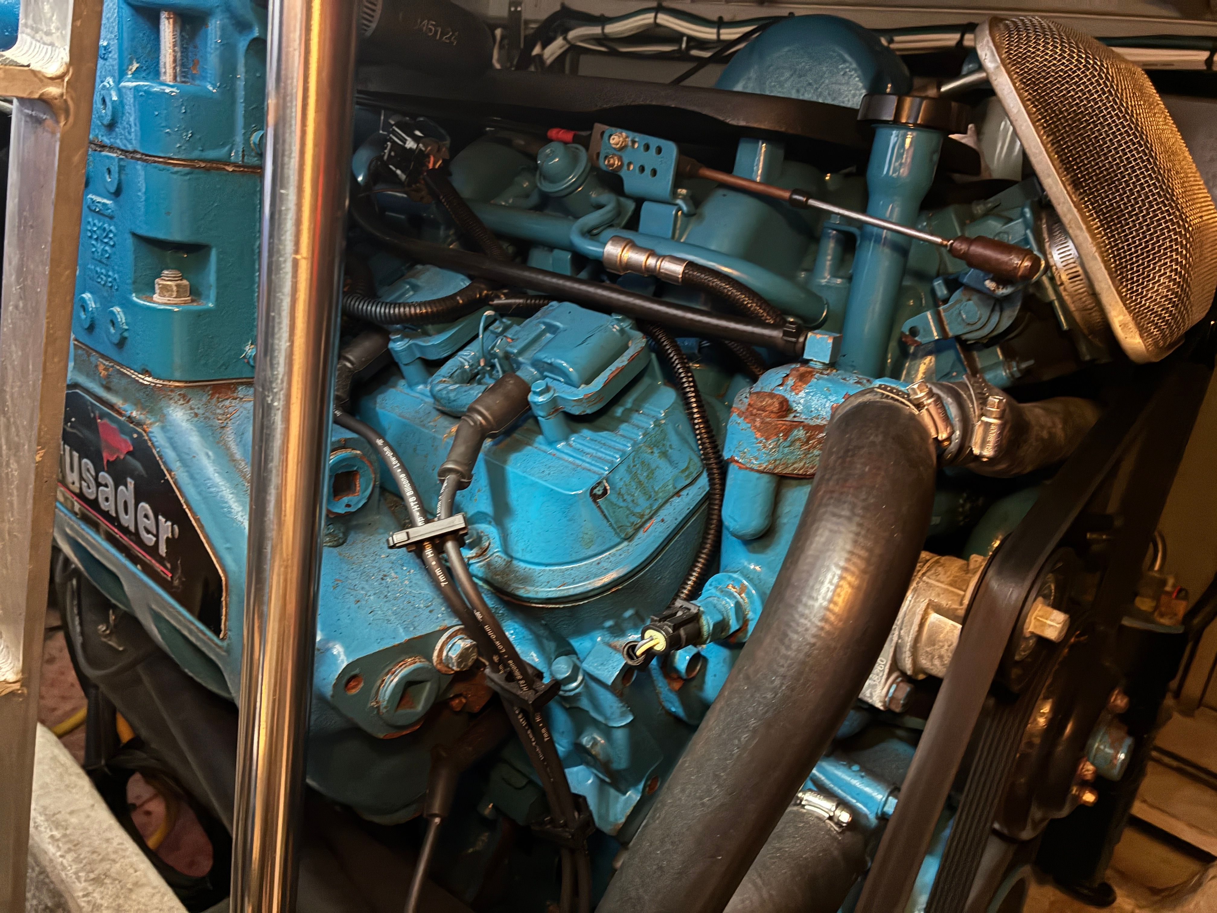 A blue-painted engine in an engine room, surrounded by pipes and cables.