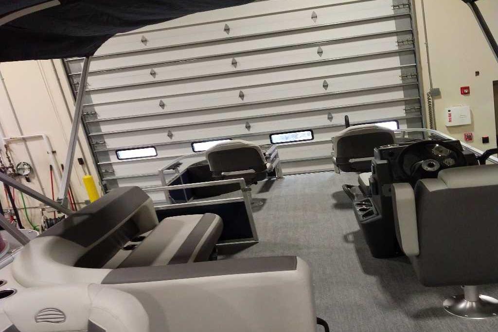 2026 Sun Tracker Bass Buggy 18 DLX interior with seating and steering console in a garage.