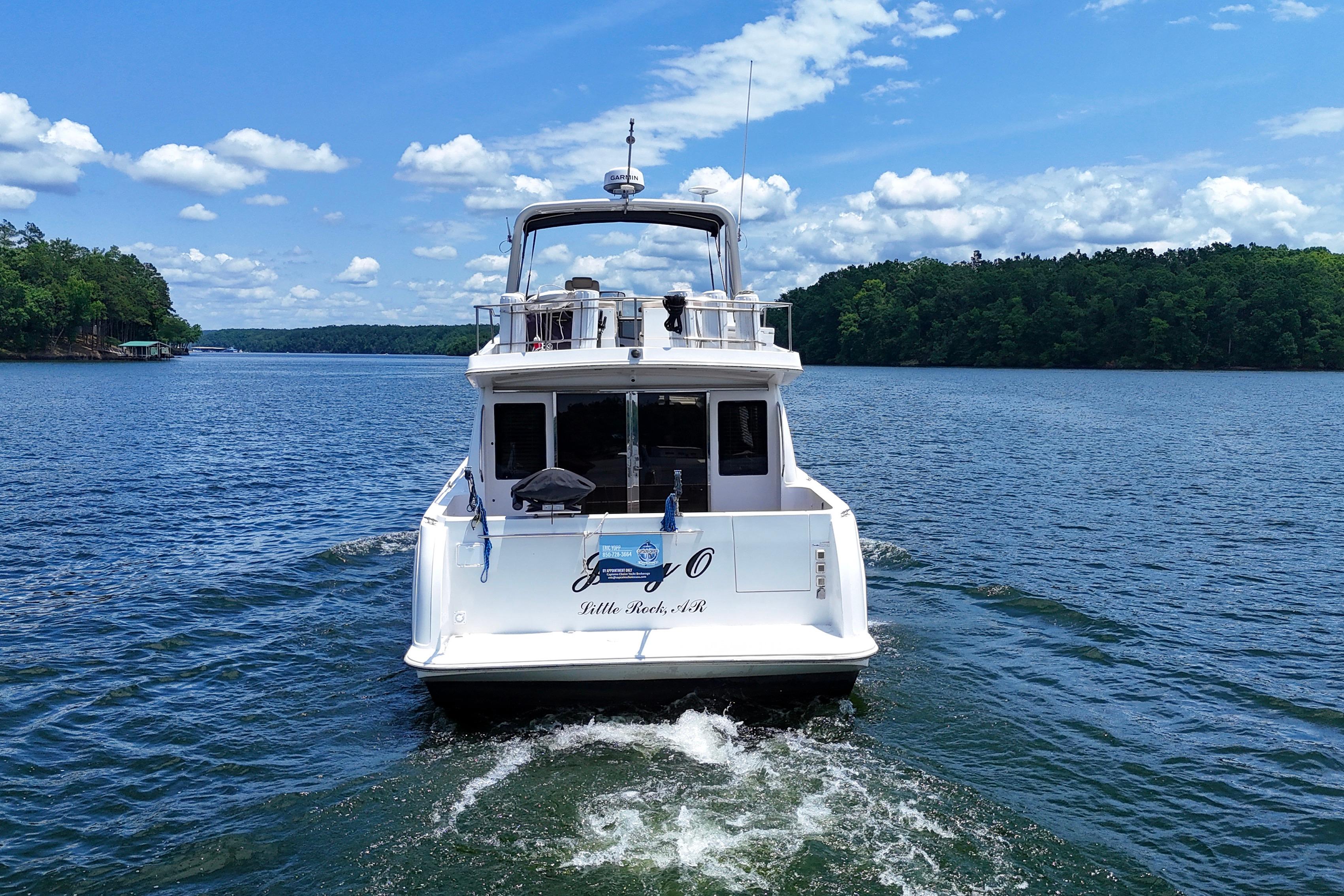 2007 Navigator 5100 yacht cruising on a scenic lake under a clear blue sky.