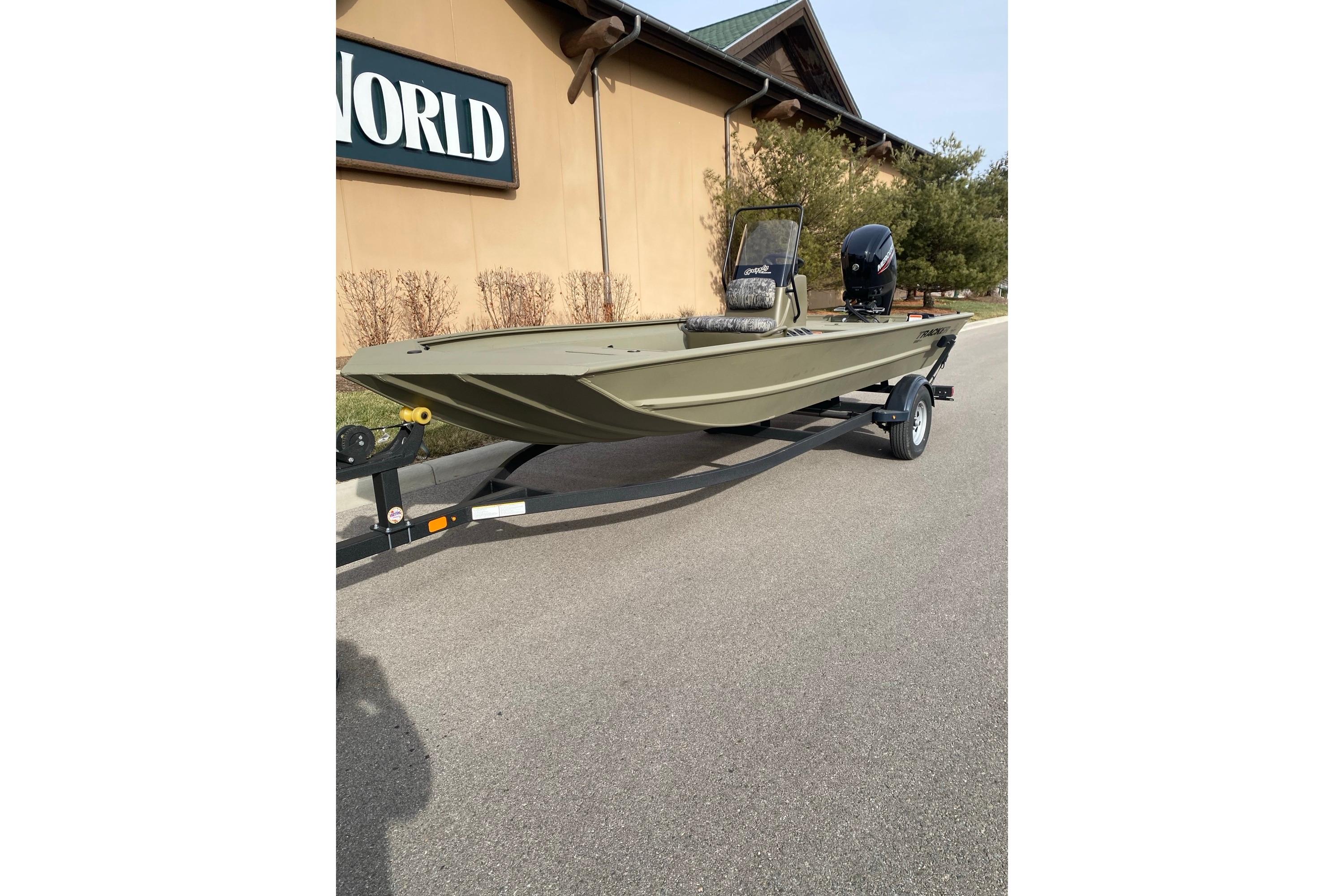 2026 Tracker Grizzly 1860 CC boat on trailer, parked outside a building.