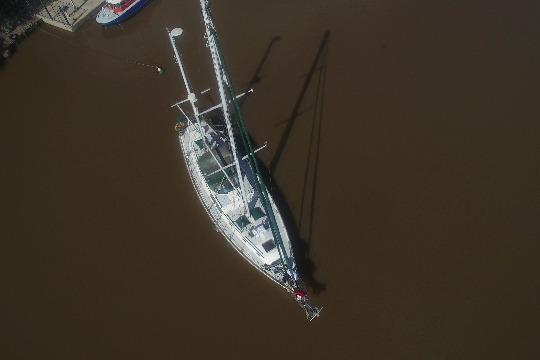 Aerial view of a 1977 Gulfstar 50 sailboat on calm brown water.
