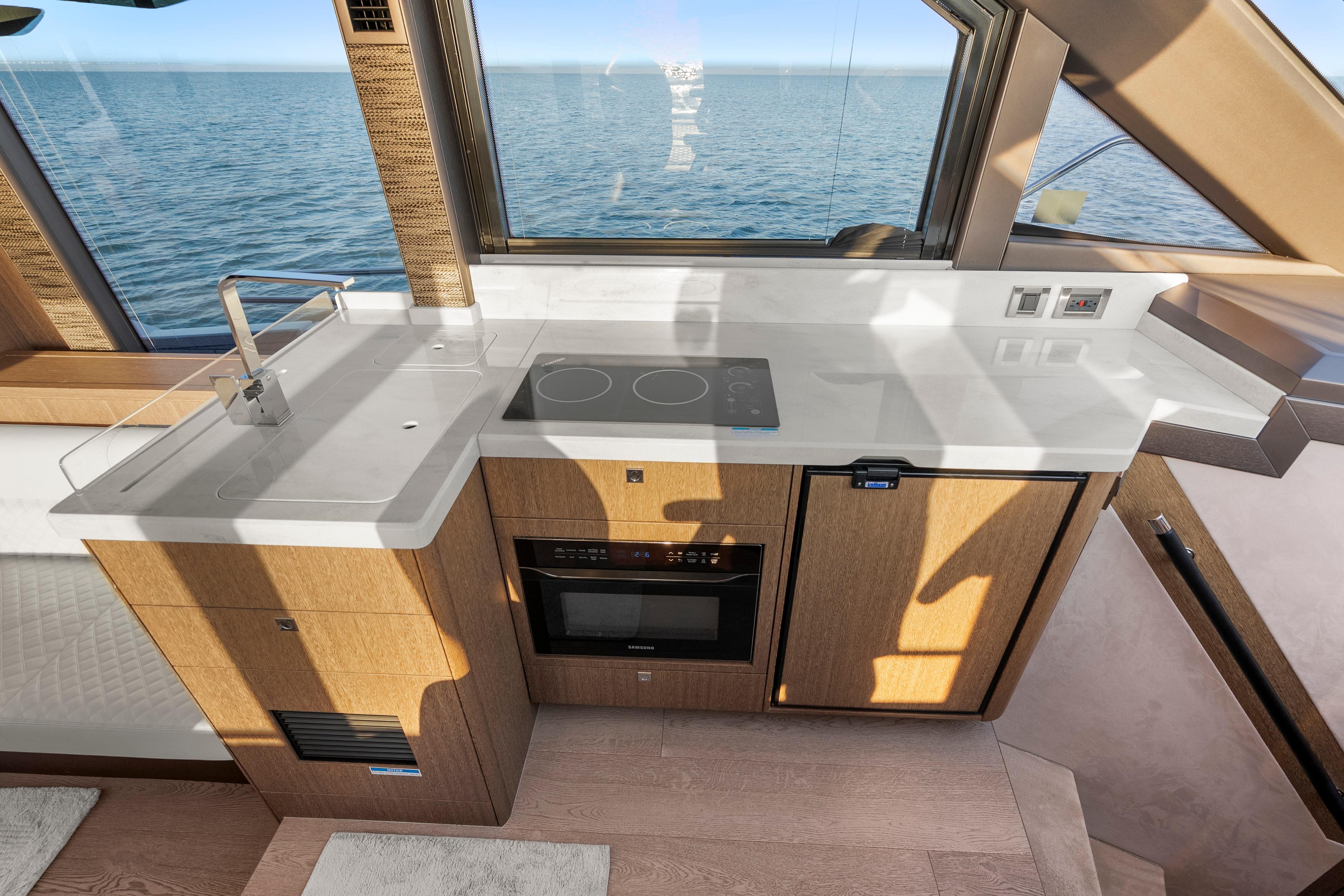 Modern kitchen on 2023 Galeon 400 Fly yacht with ocean view, featuring sleek countertops and appliances.