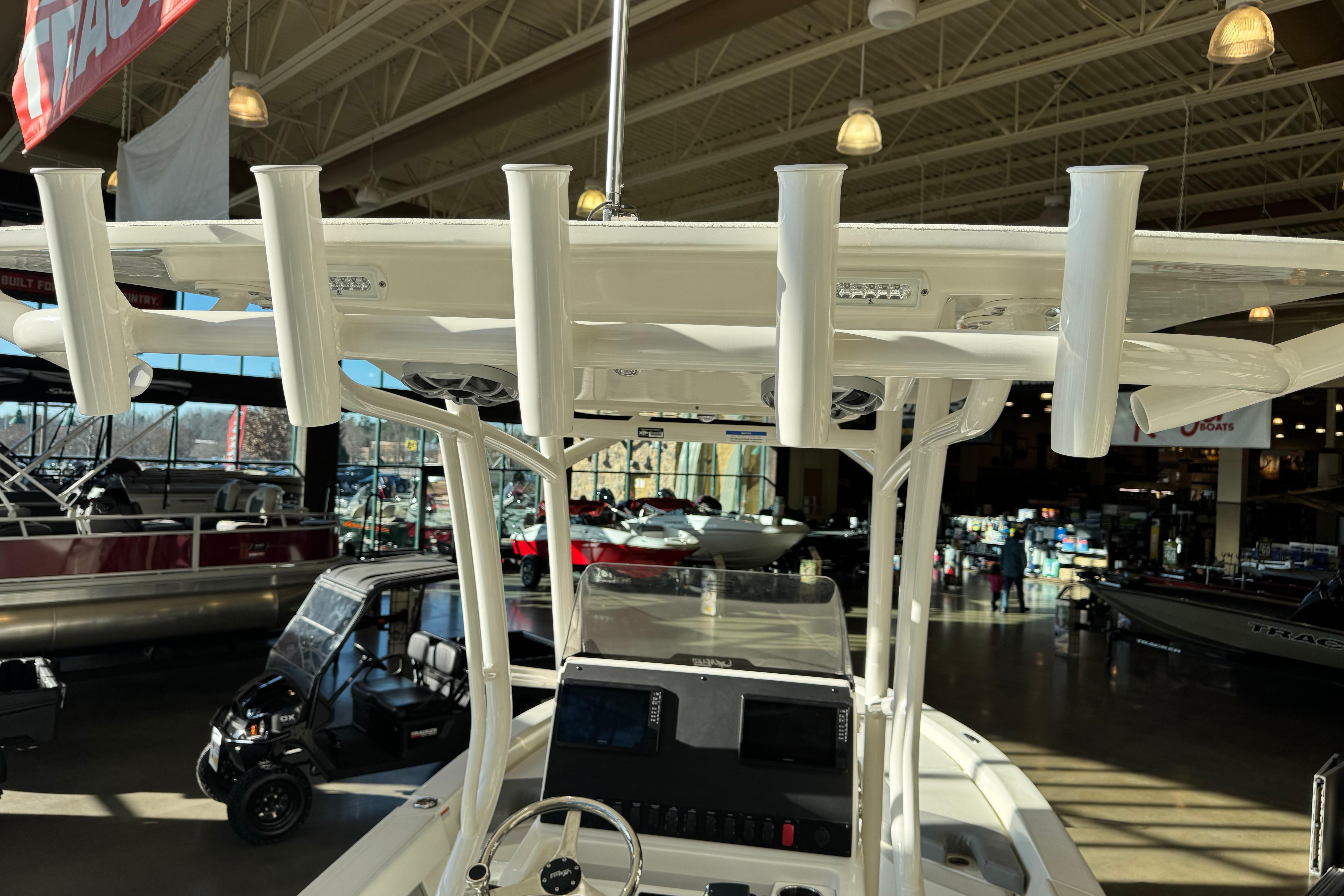 2026 Mako 24 APEX boat interior with rod holders in a showroom setting.