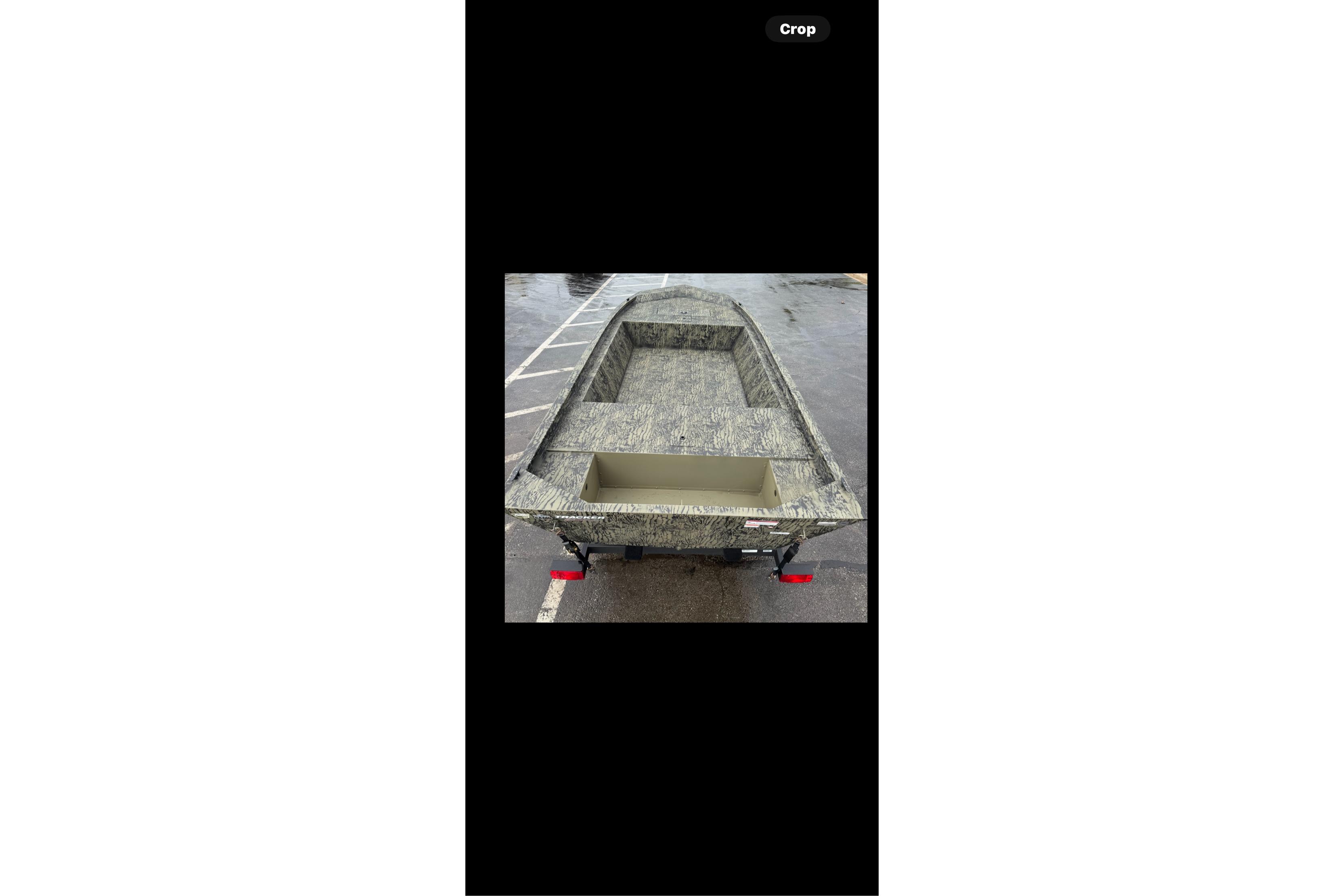 2026 Tracker Grizzly 1648 Utility boat on trailer, parked on wet pavement.