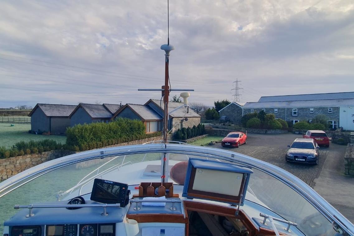 1989 Fairey Spearfish MKIII boat docked near countryside homes and parked cars.