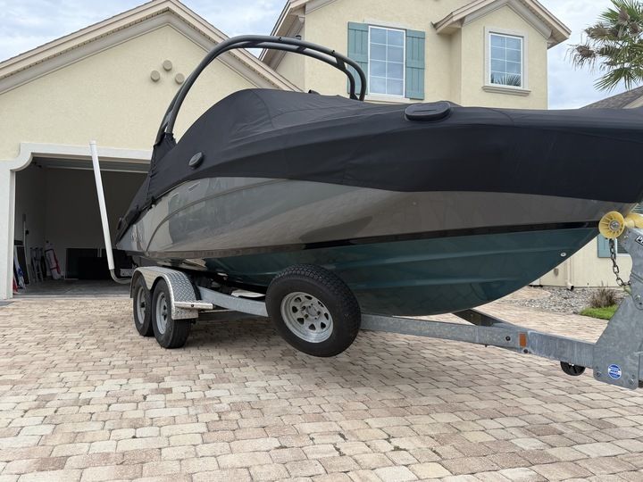 A 2022 Yamaha 212SD boat on a trailer in front of a house.