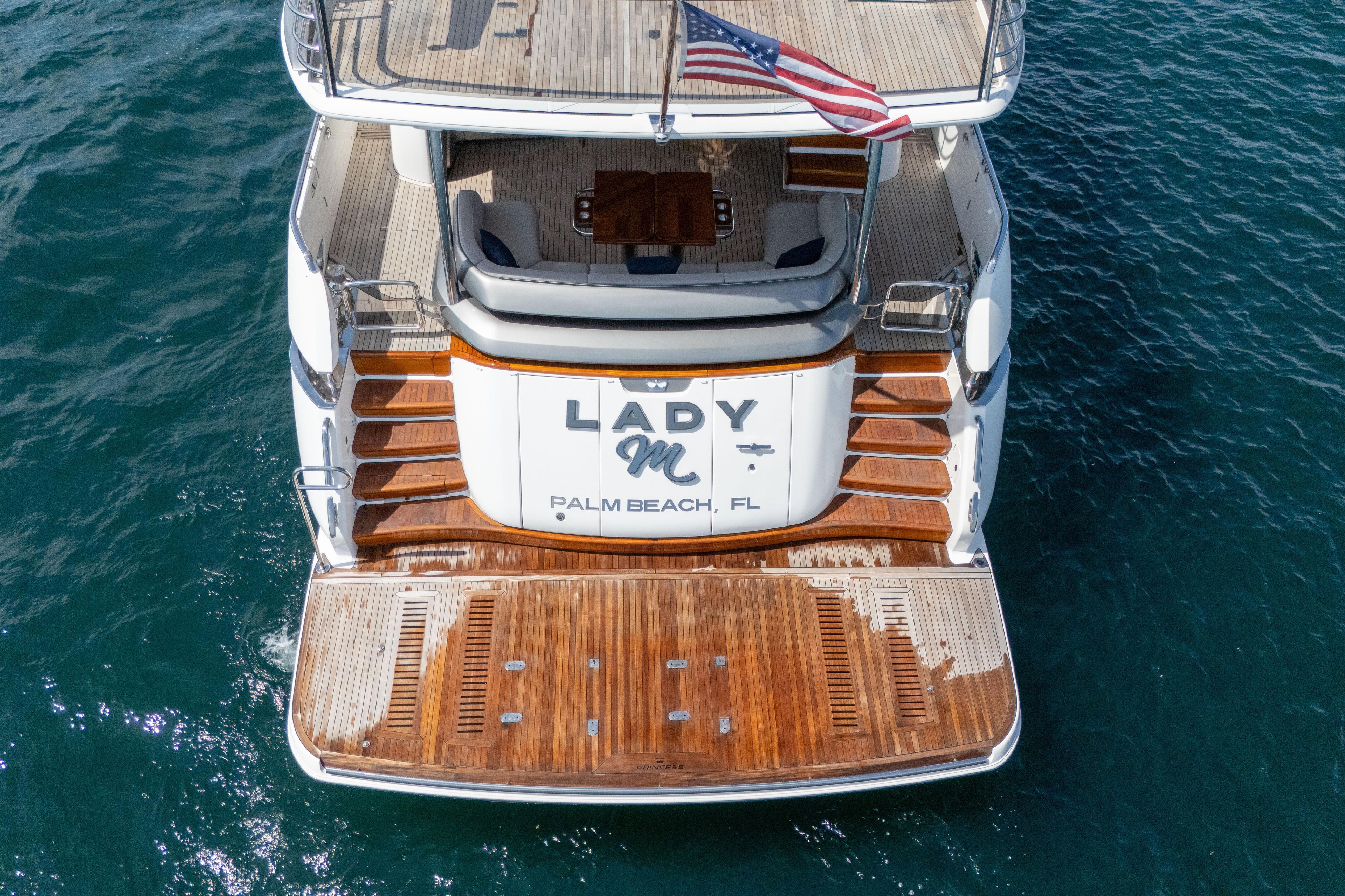 Luxury yacht "Lady M" docked, Princess Y85 model, 2020, Palm Beach, wooden deck, American flag.