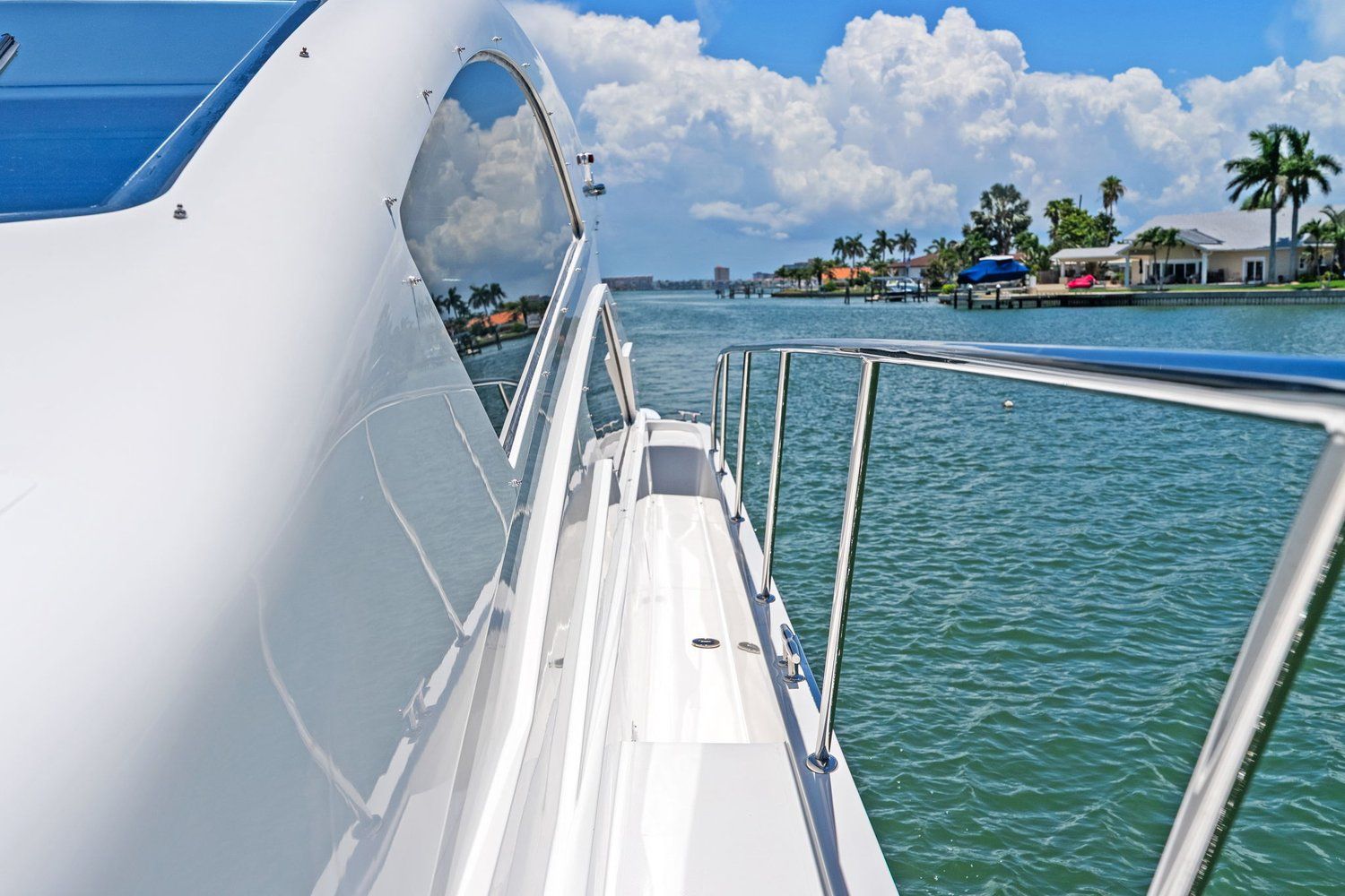 Side view of a white catamaran on calm water with palm trees in the background.