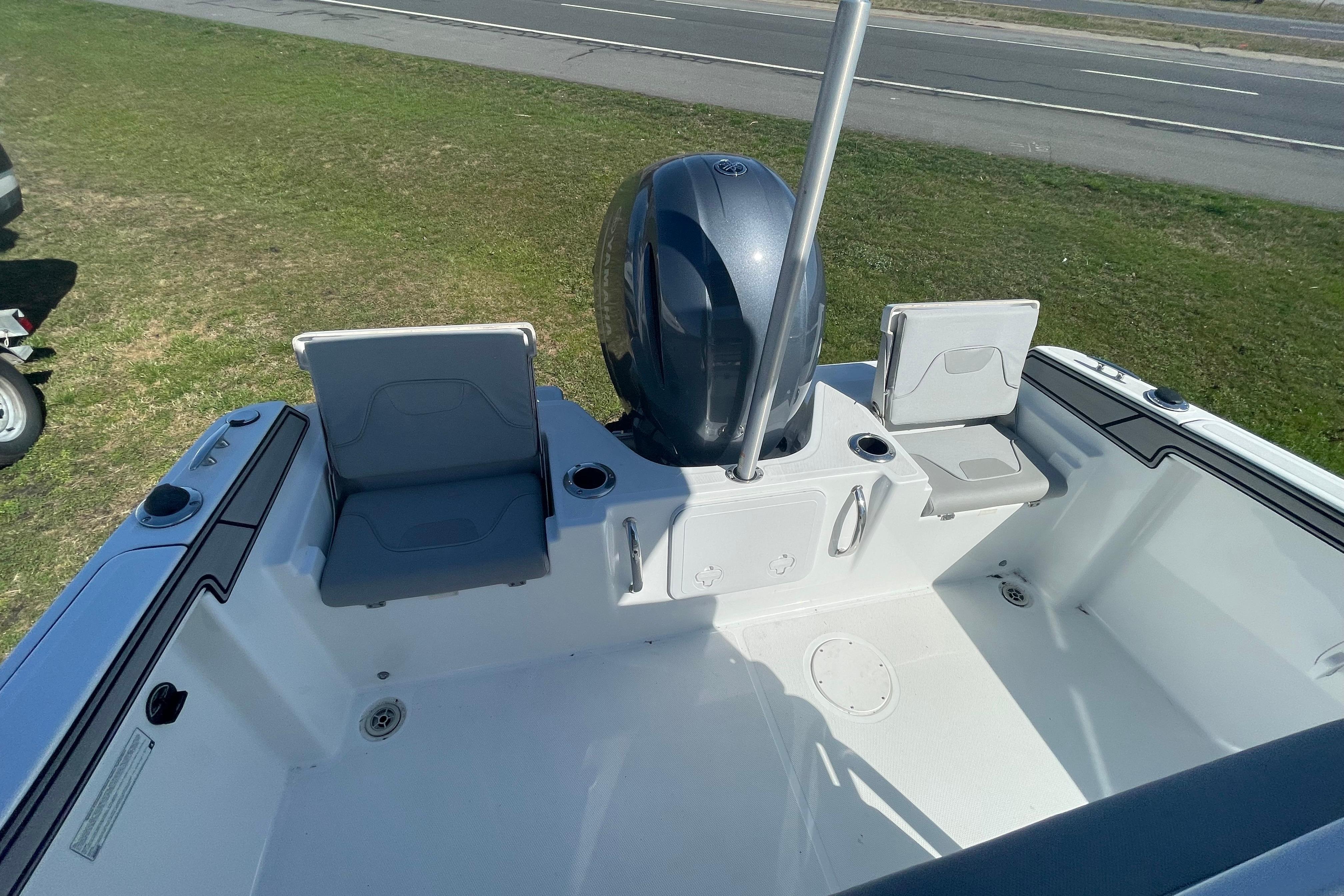 2022 Wellcraft 202 Fisherman boat interior with seating and motor, parked on grass.