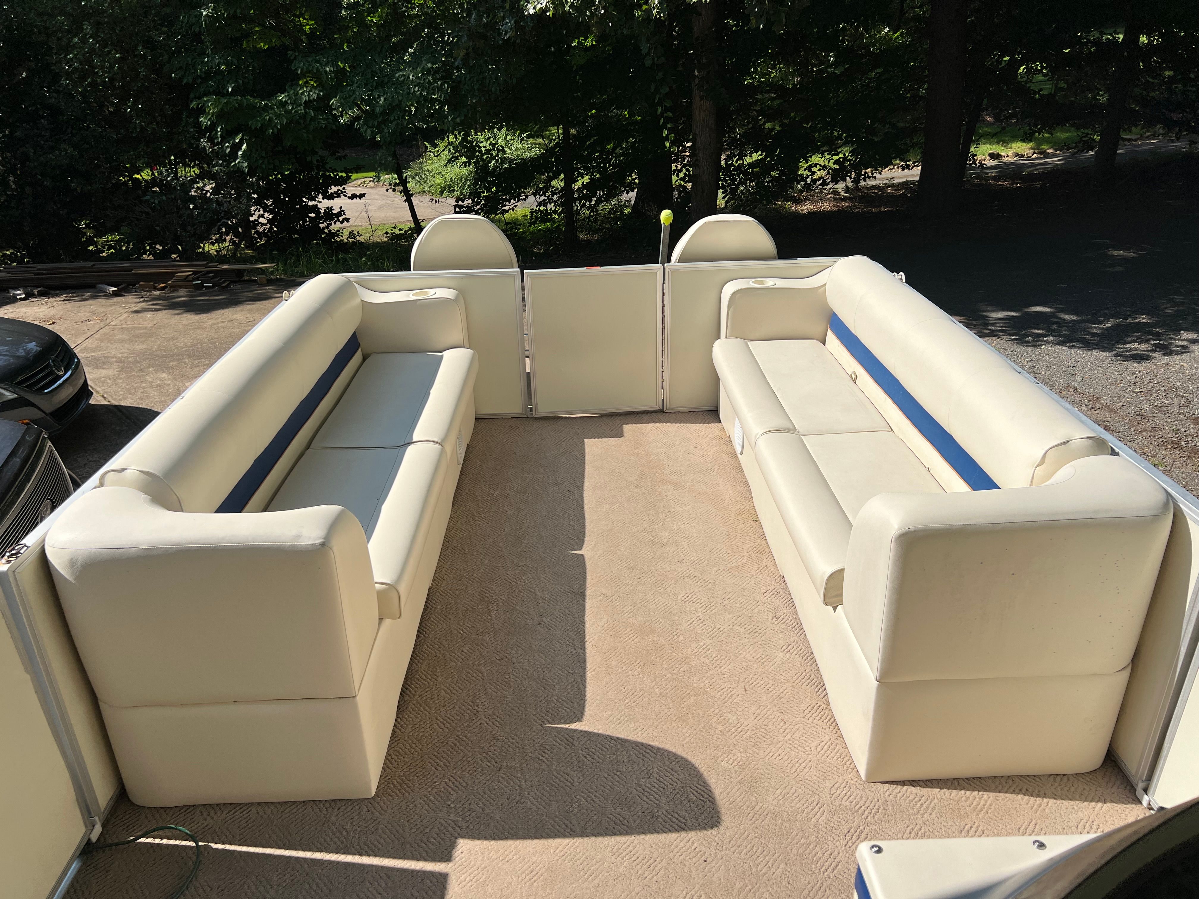 Interior of a 2003 Crest 24’ Sport pontoon boat with cream seats and blue accents.