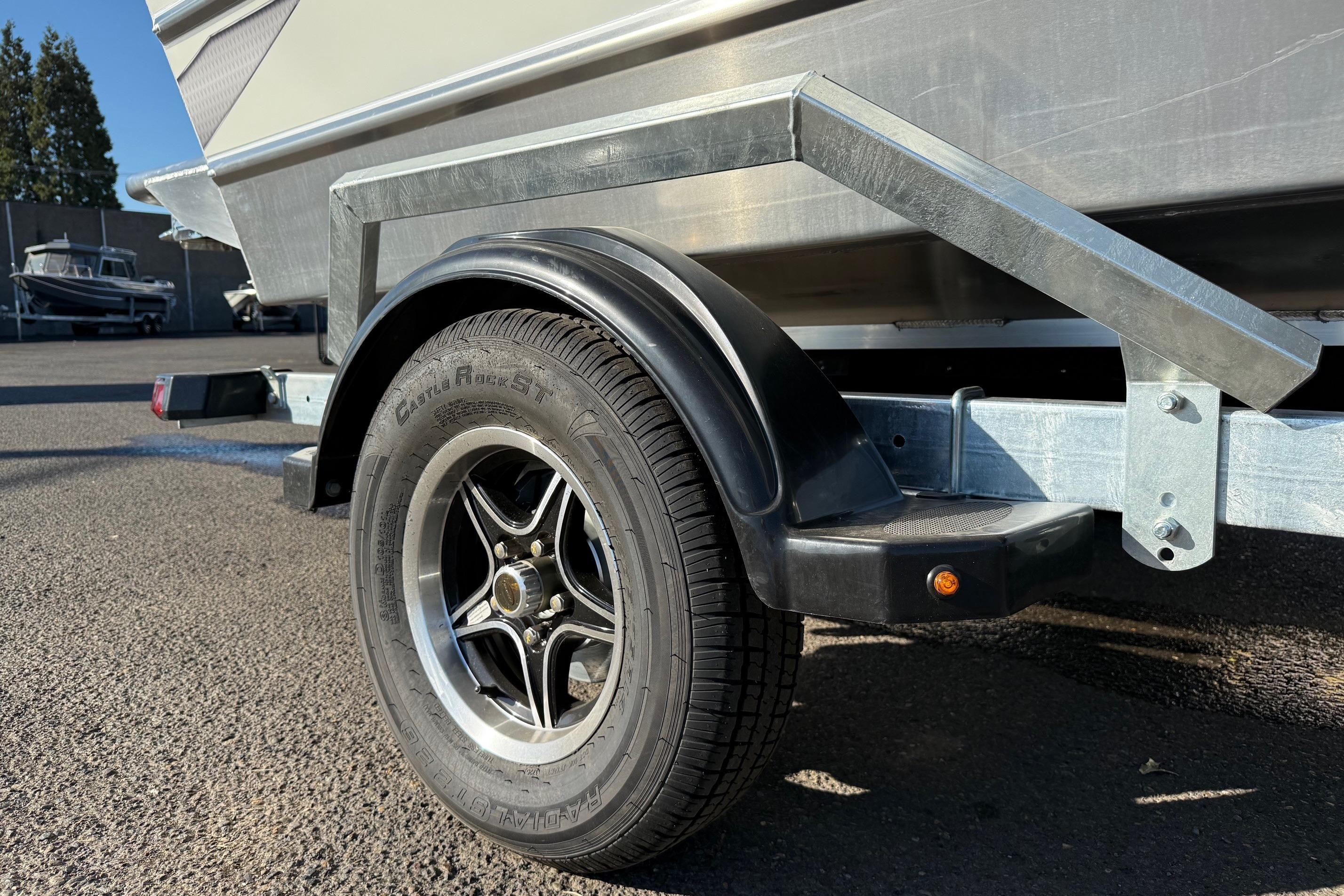 Trailer wheel of 2026 Thunder Jet 185 Luxor boat, parked on asphalt.