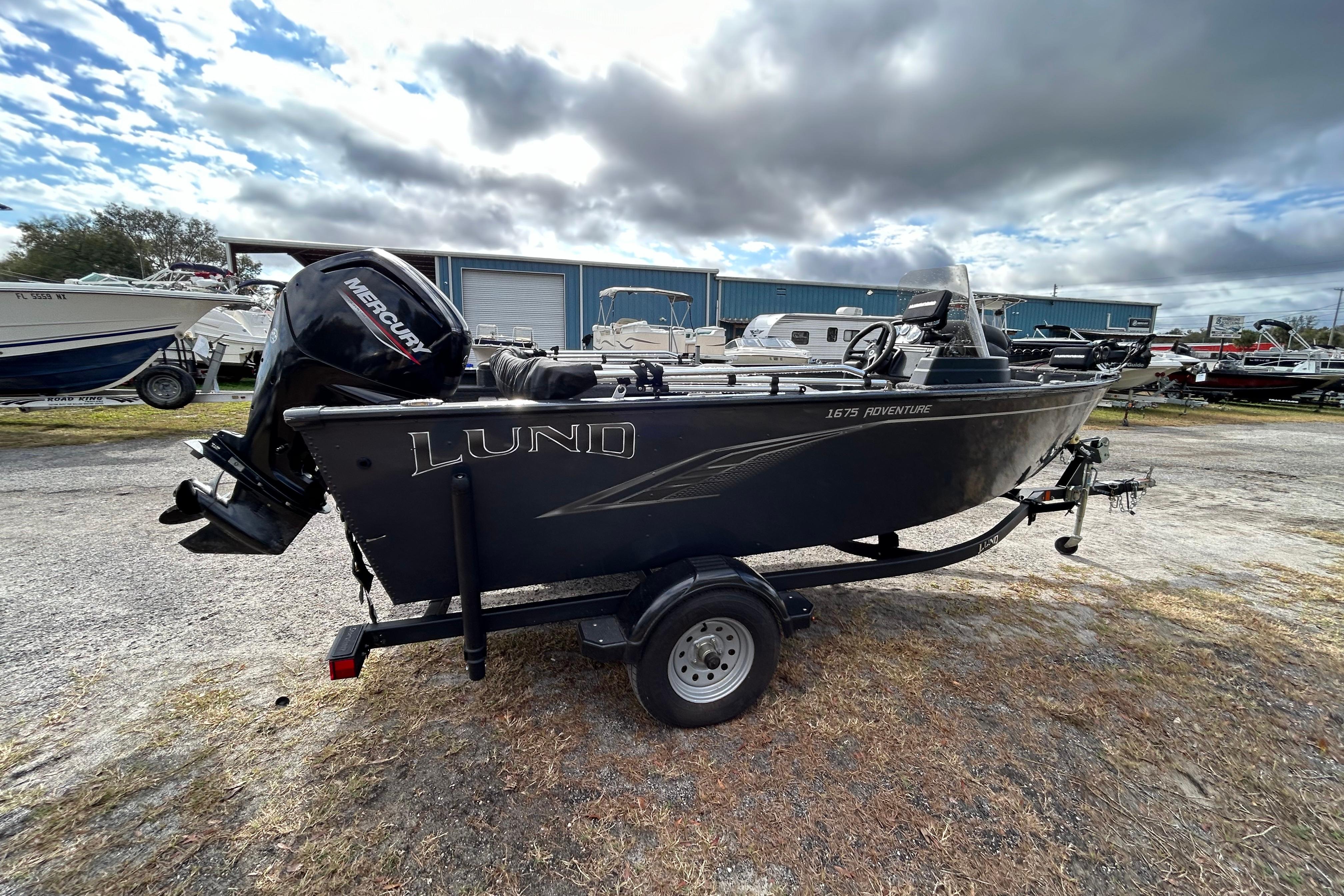 2021 Lund 1675 Adventure SS boat with Mercury engine on trailer, parked outdoors.