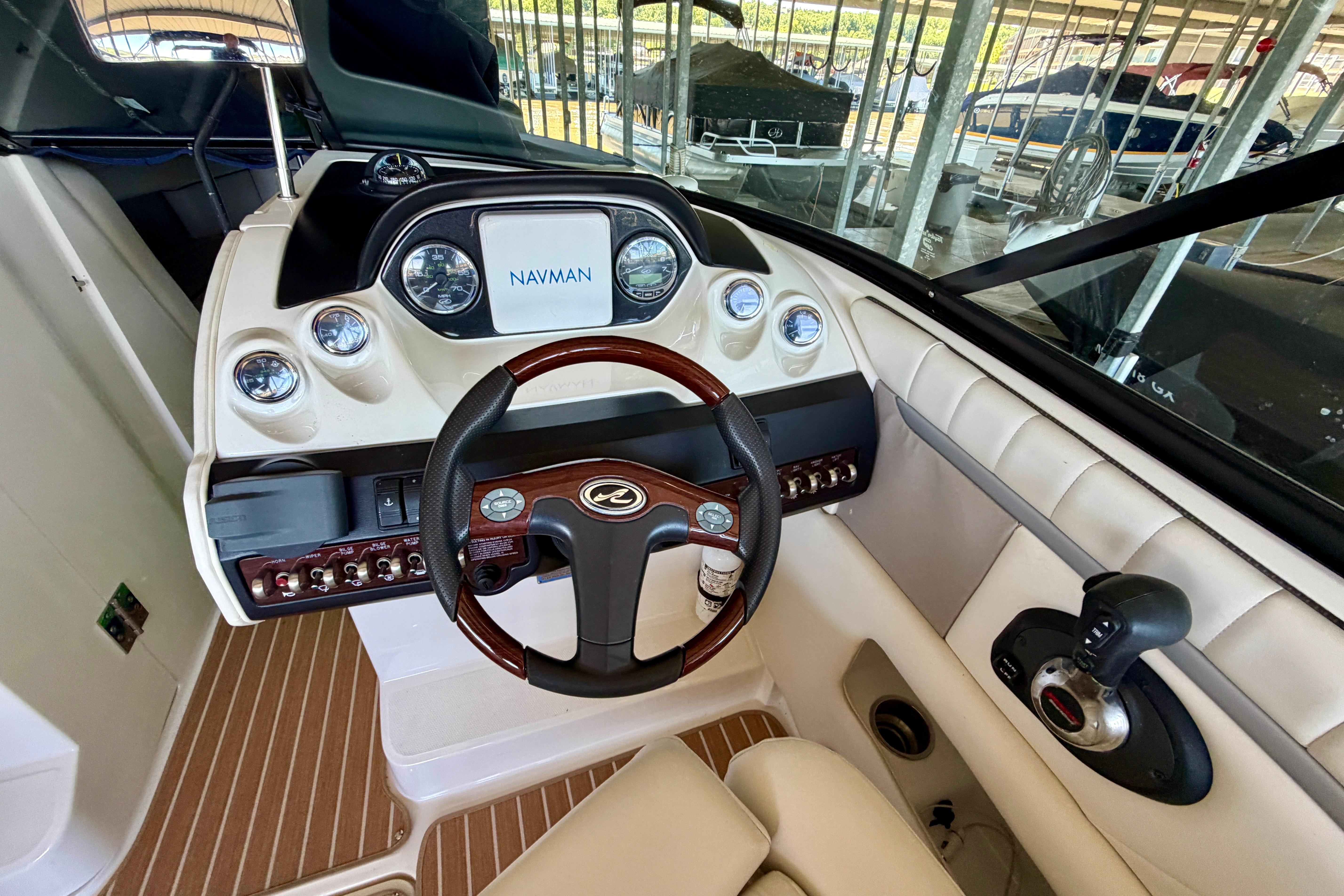 2007 Sea Ray 270 SLX boat dashboard with Navman display and wood-accented steering wheel.