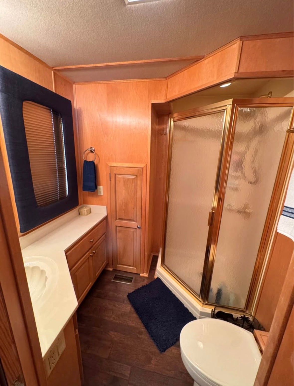 Bathroom in a 1998 Stardust Cruisers houseboat with shower and wood paneling.