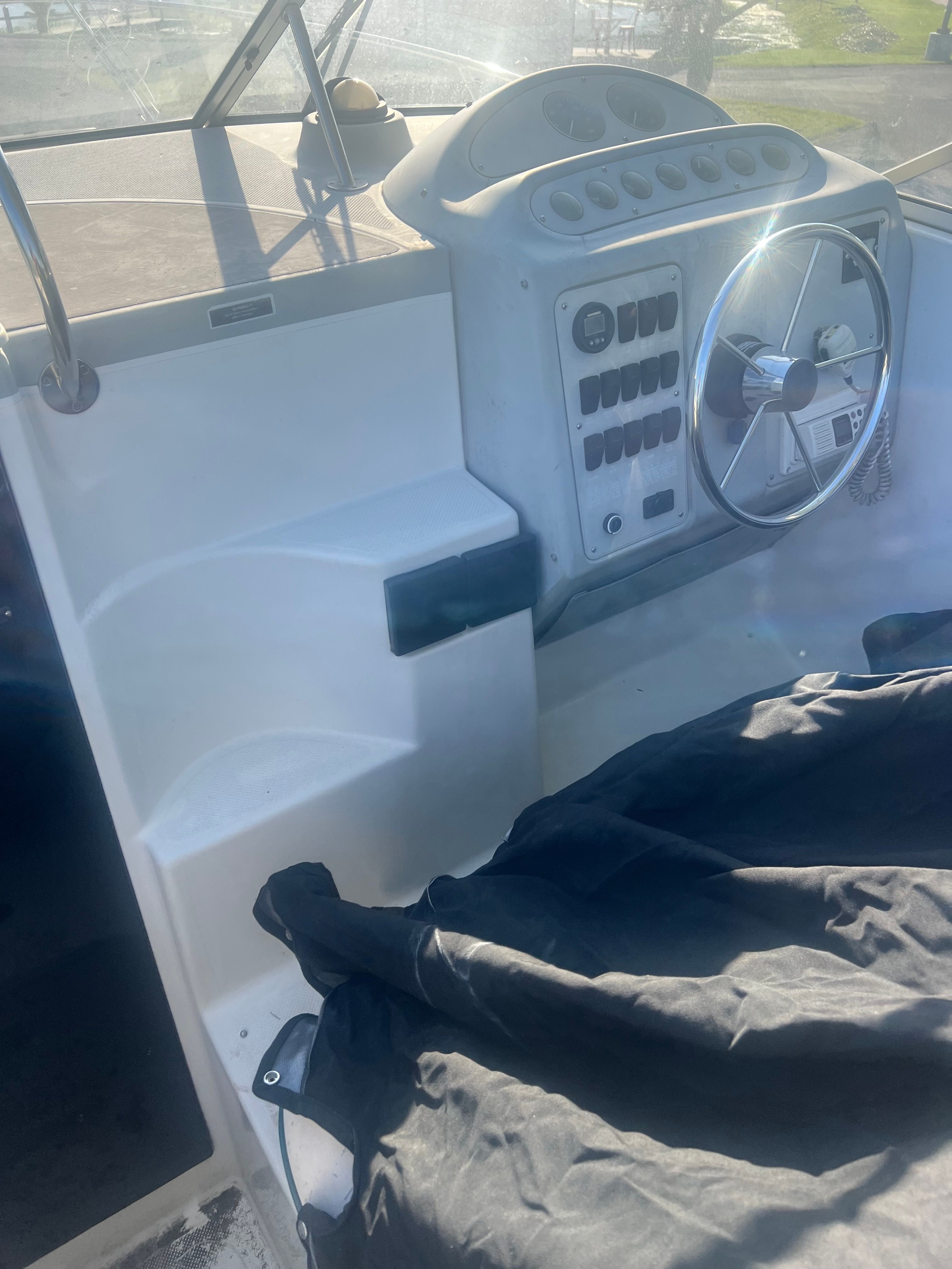 The image shows a boat's helm with a steering wheel and various instruments.