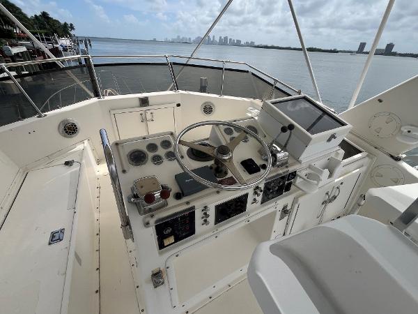 Helm of 1985 Hatteras 45 Convertible yacht with ocean view and city skyline.