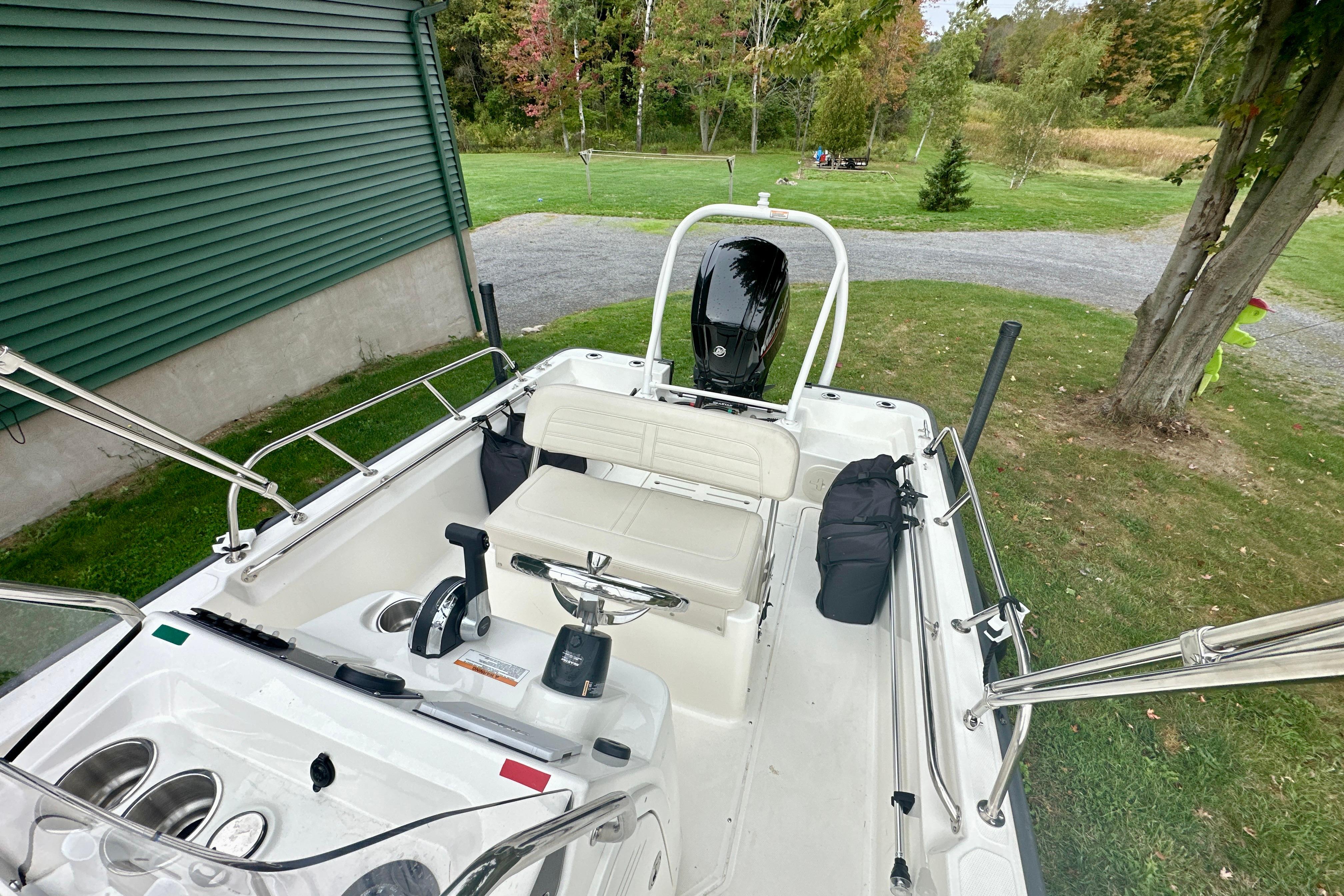 2024 Boston Whaler 170 Montauk boat interior with seating and controls, parked on grass.