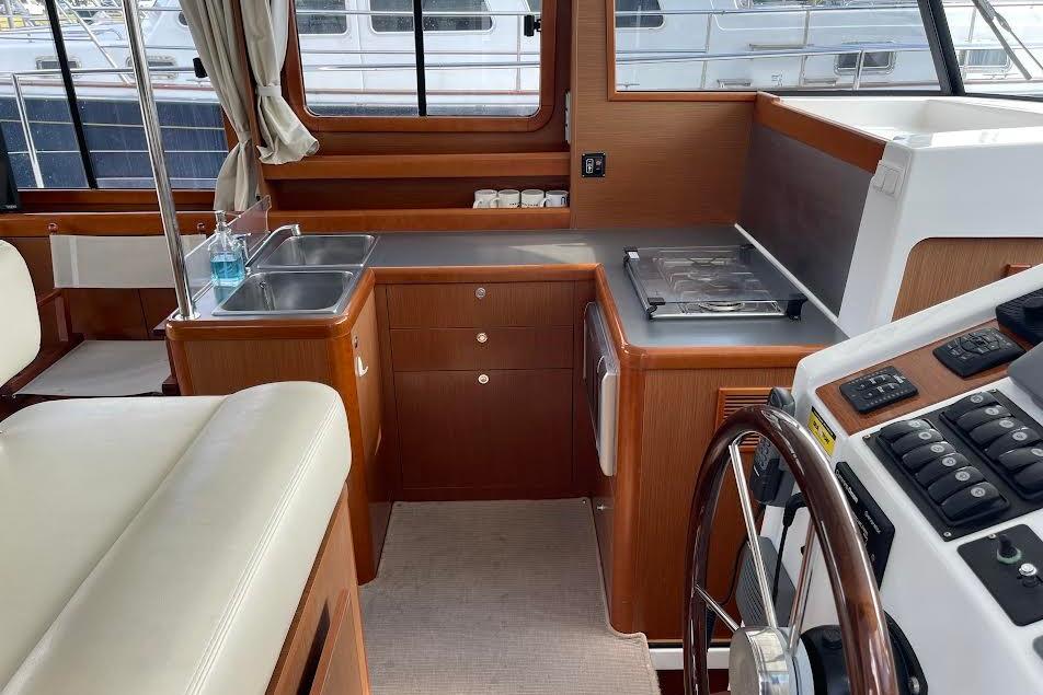 Interior of 2012 Beneteau Swift Trawler 34, featuring a compact kitchen and helm station.