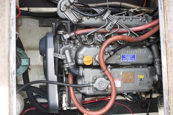 An engine compartment with a large engine and various hoses and cables.