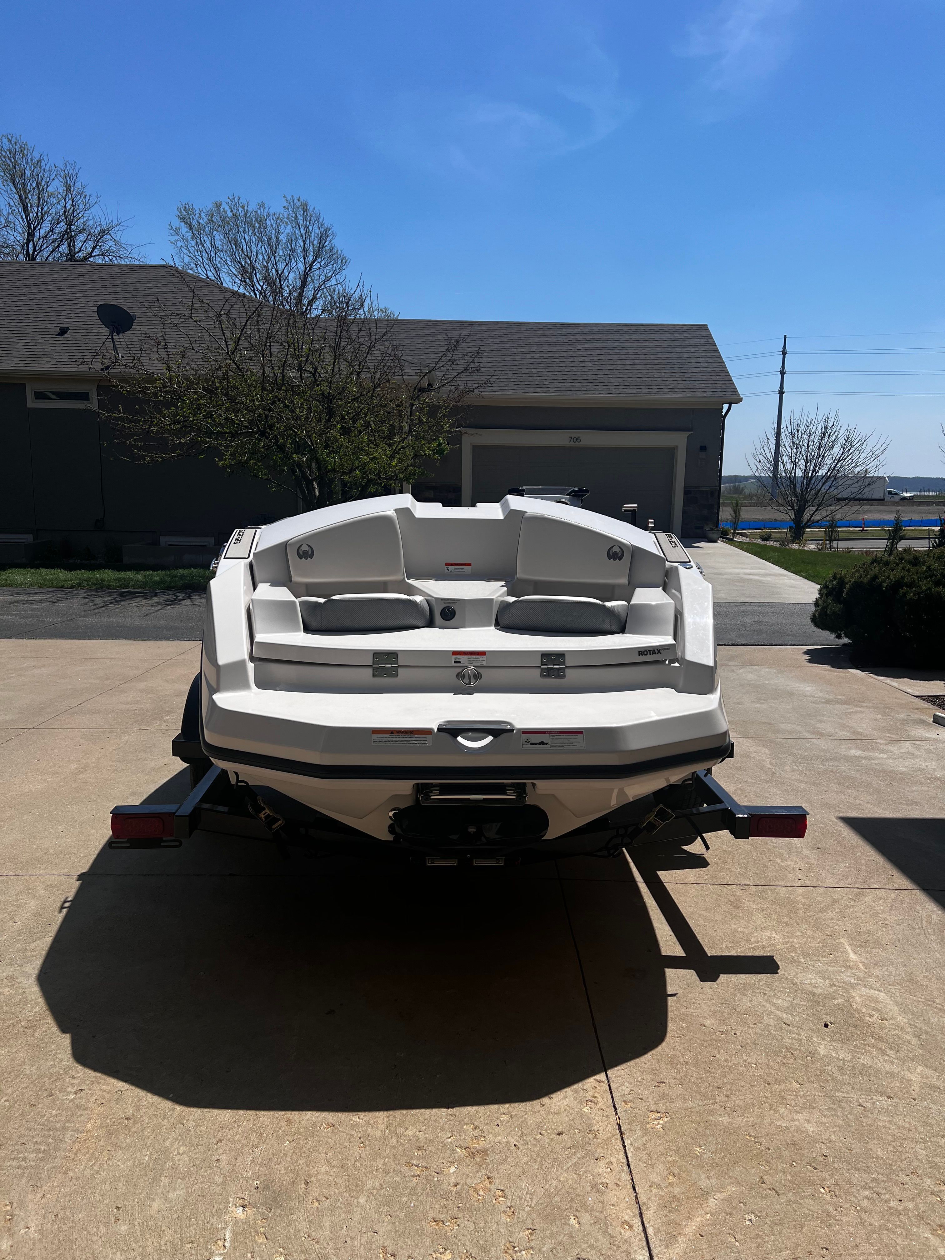 A white Scarab 165 G boat is on a trailer in a driveway.