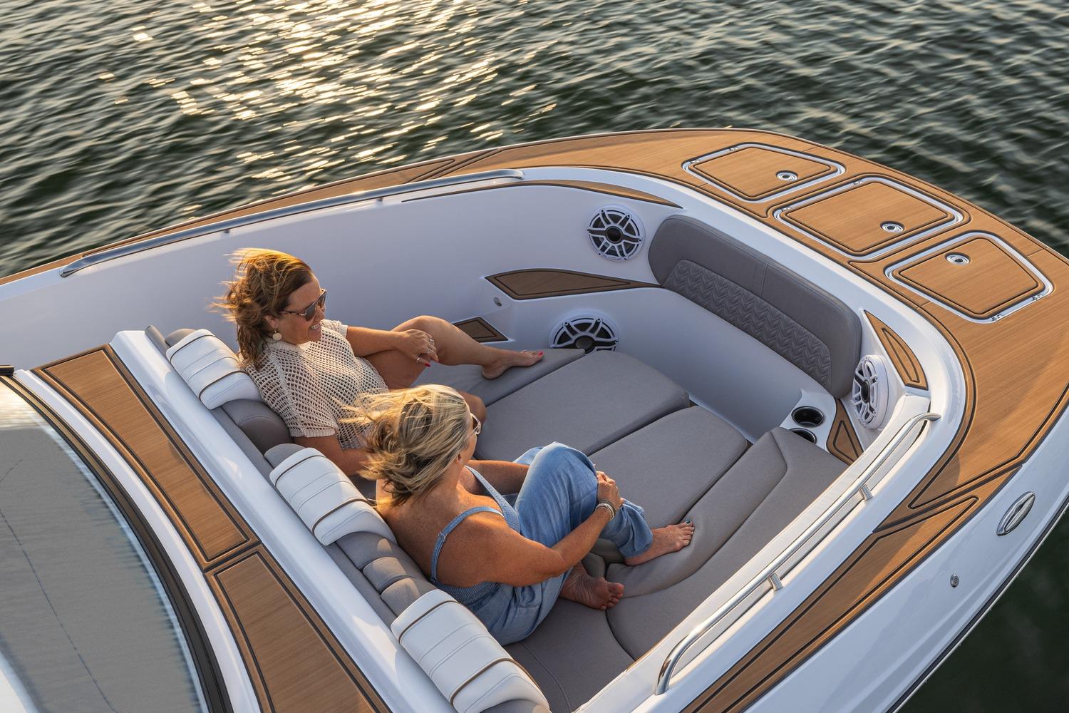 2026 Hurricane SunDeck 3200 OB boat with two people relaxing on deck, enjoying the water.