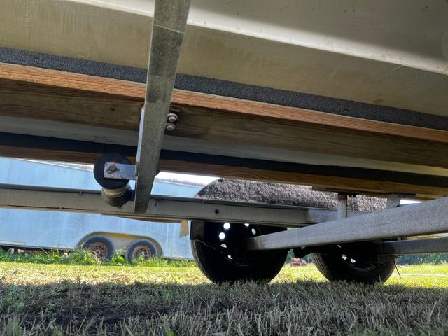 A boat trailer with two wheels is parked on grass.