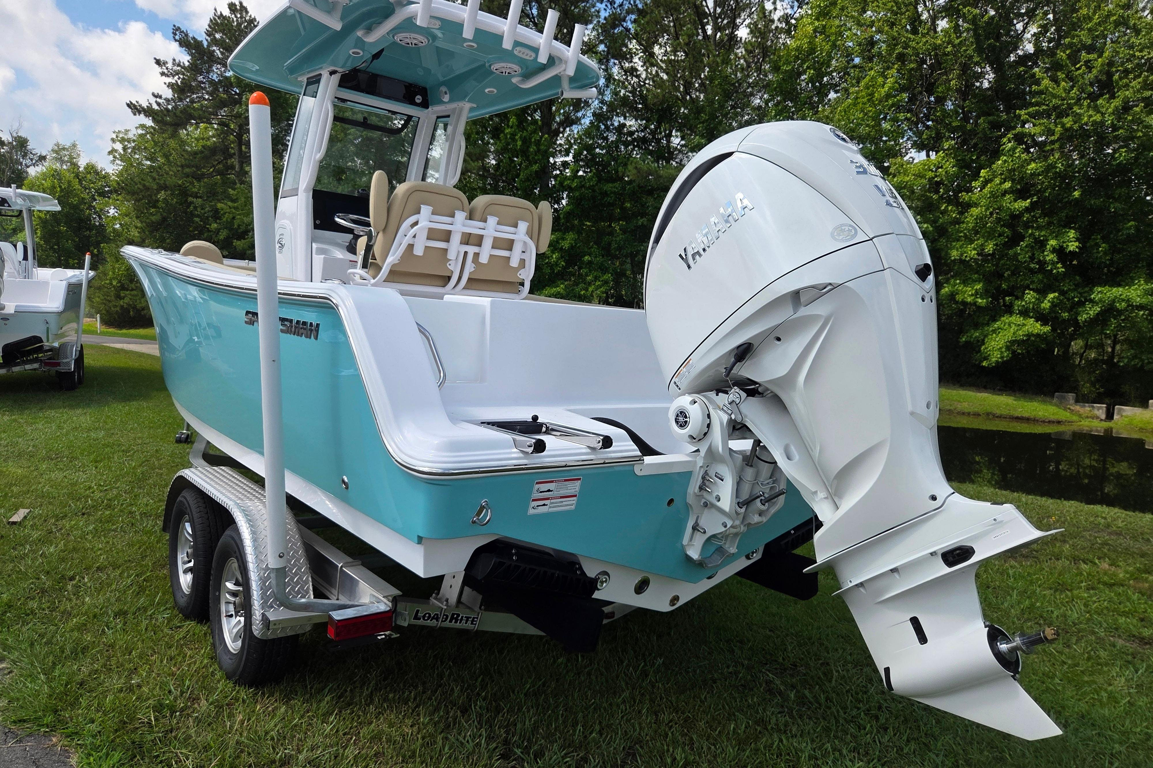 2026 Sportsman Open 232 Center Console boat with Yamaha engine on trailer, parked on grass.