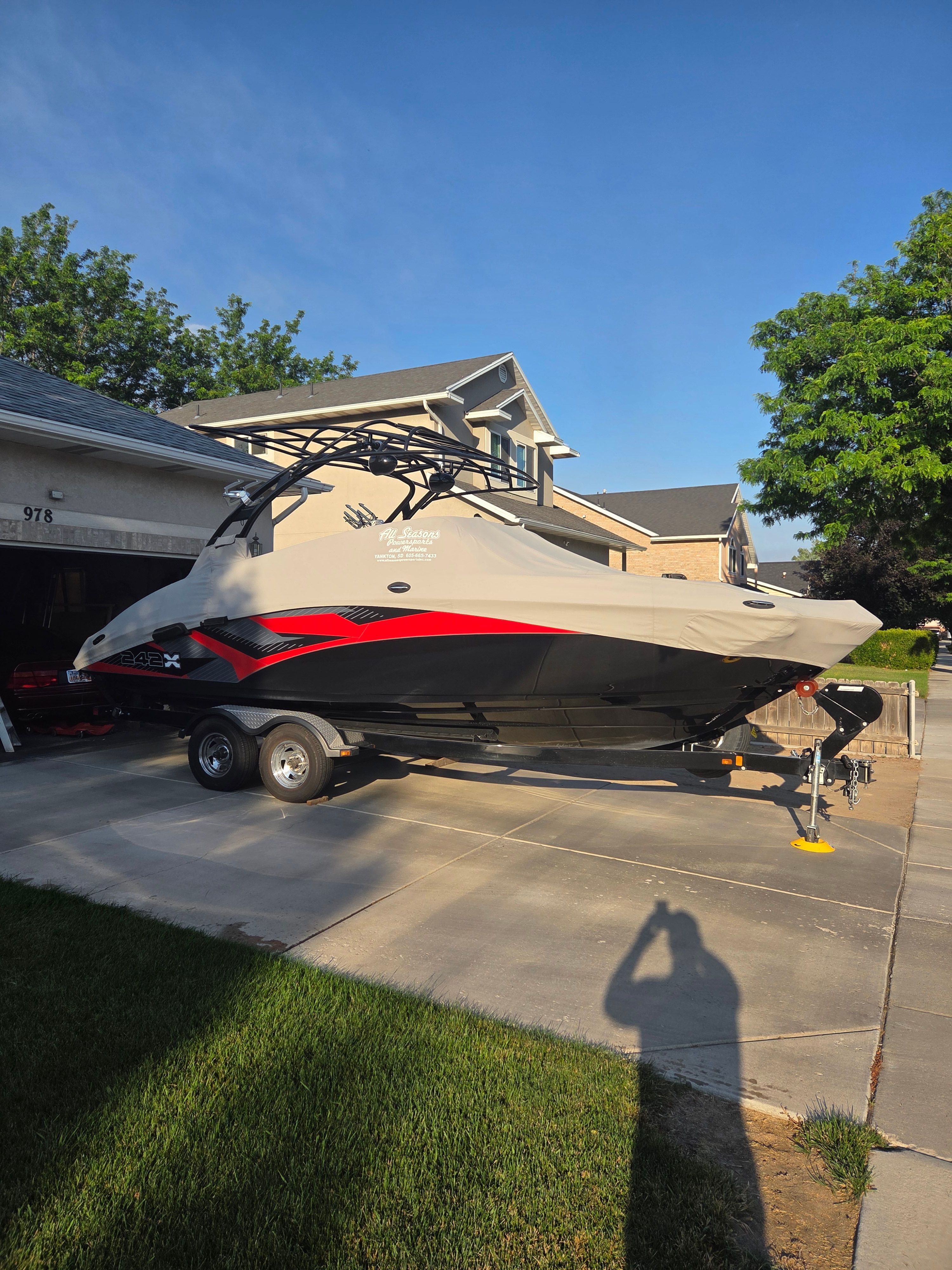 A 2016 Yamaha 242X E-Series boat on a trailer in a driveway.